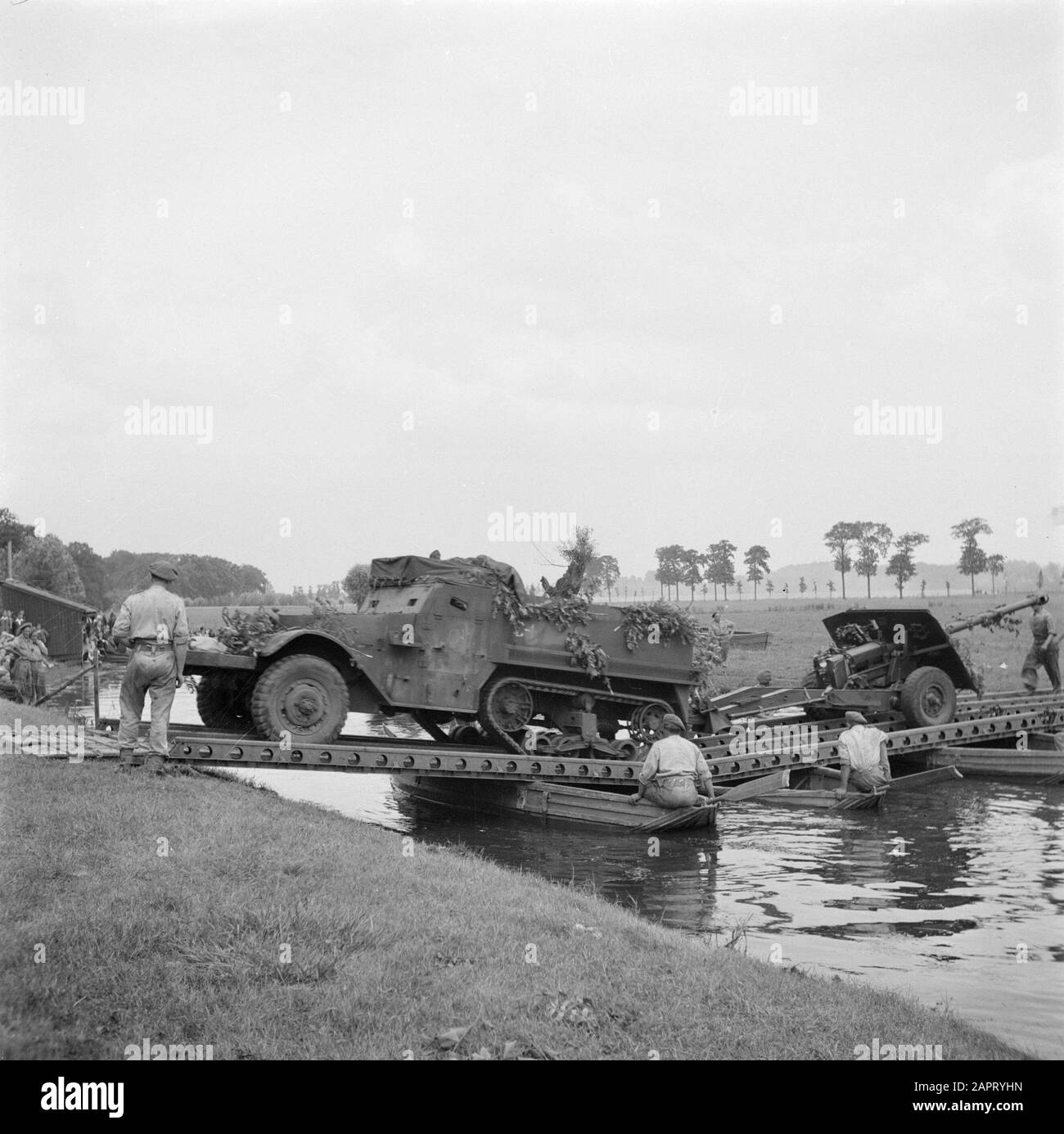 Military Reportage  A military exercise. A river must be crossed. A halftrack is transferred via a pontoon bridge Date: 1939 The factual accuracy of this description or the file name is disputed.Reason: This is a 1944 or later photo, to show a 17 pounder or half track in the Netherlands Keywords: military exercises Stock Photo
