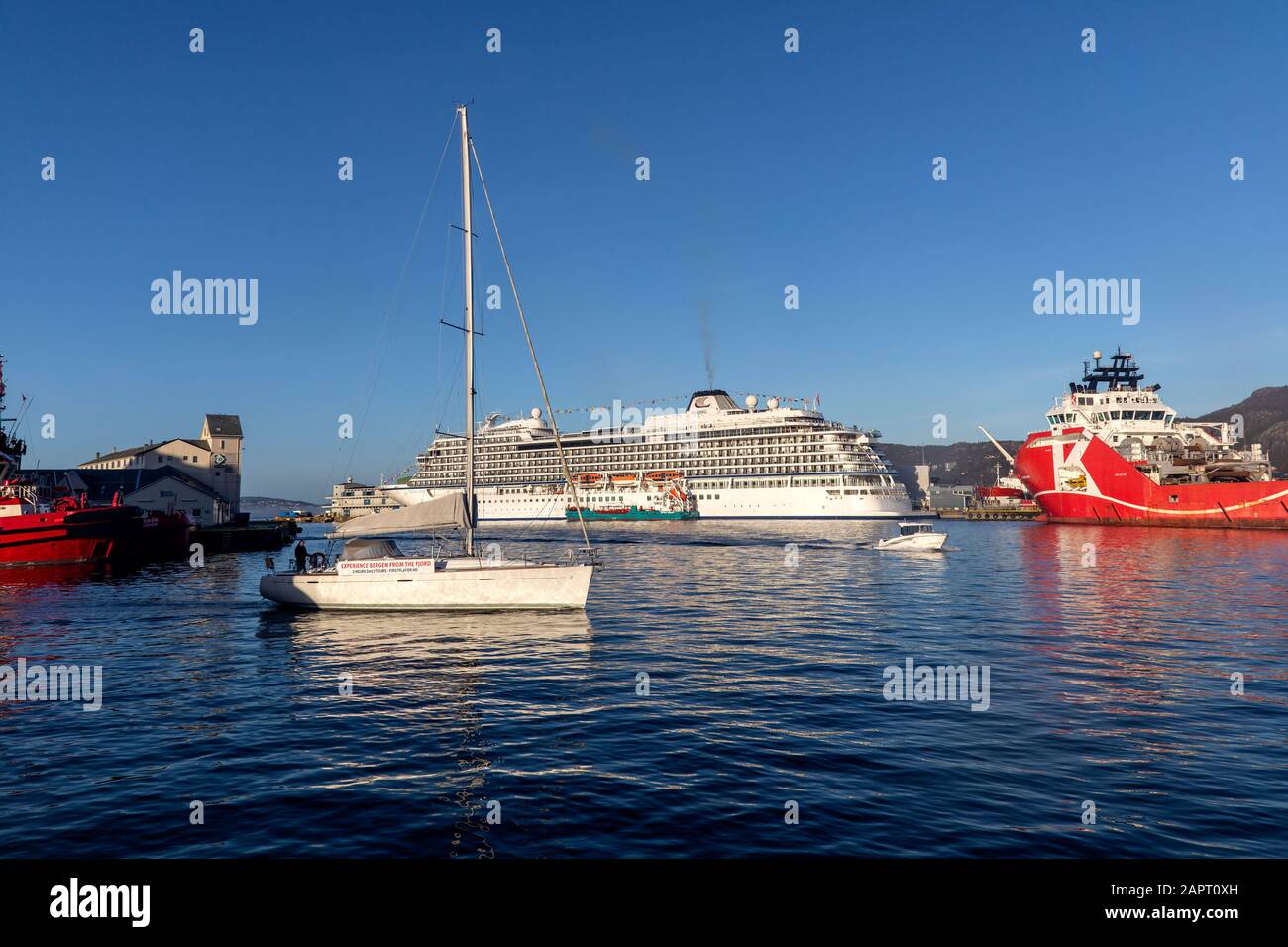 Sailboat First Player. In background, cruise ship Viking Star at Skolten quay in port of Bergen, Norway. Tanker vessel Oslo Tank alongside the large c Stock Photo