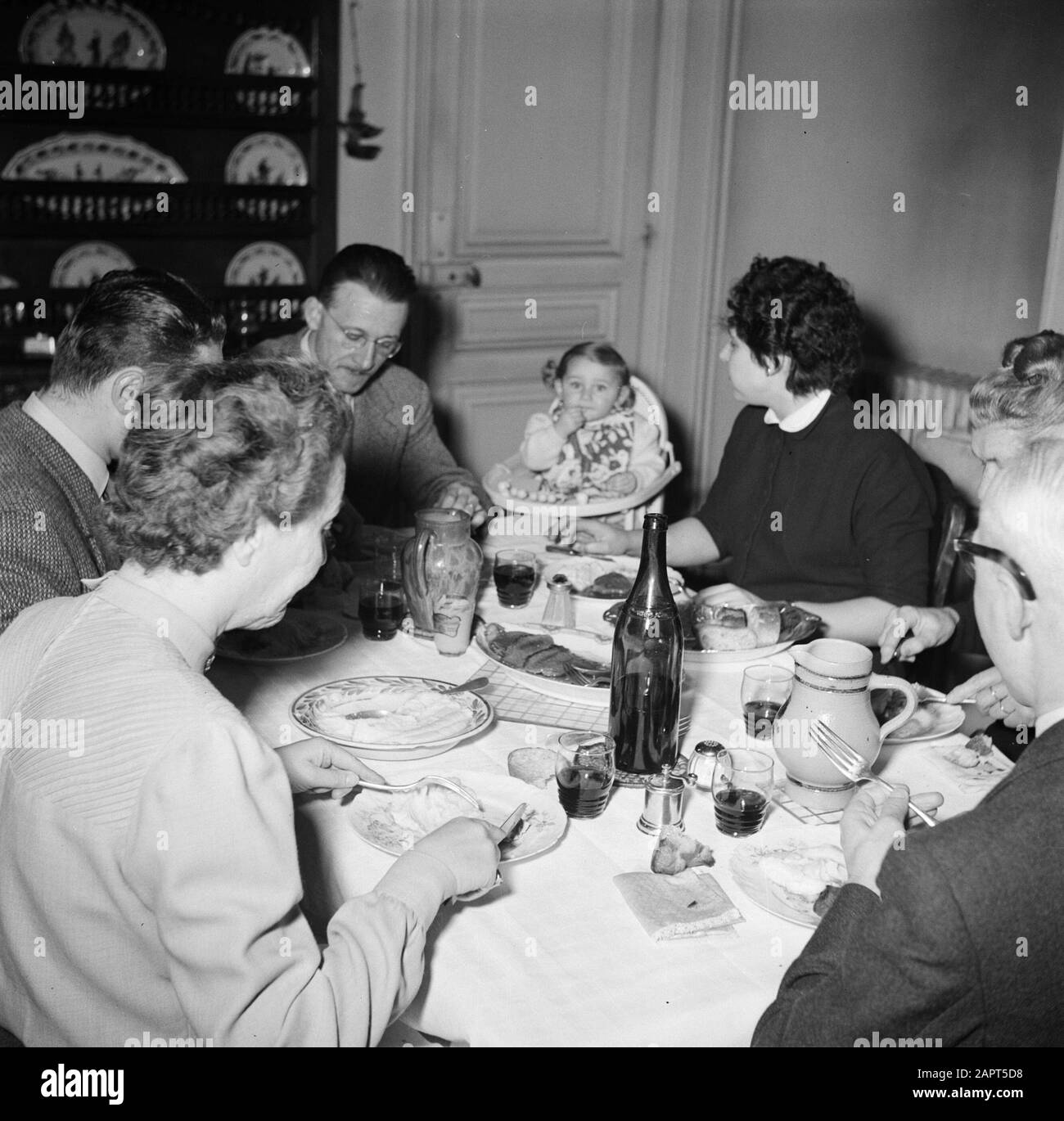Residents of an apartment building in Paris  Family with guests to the meal Date: 1950 Location: France, Paris Keywords: families, bottles, families, children, meals, wine Stock Photo