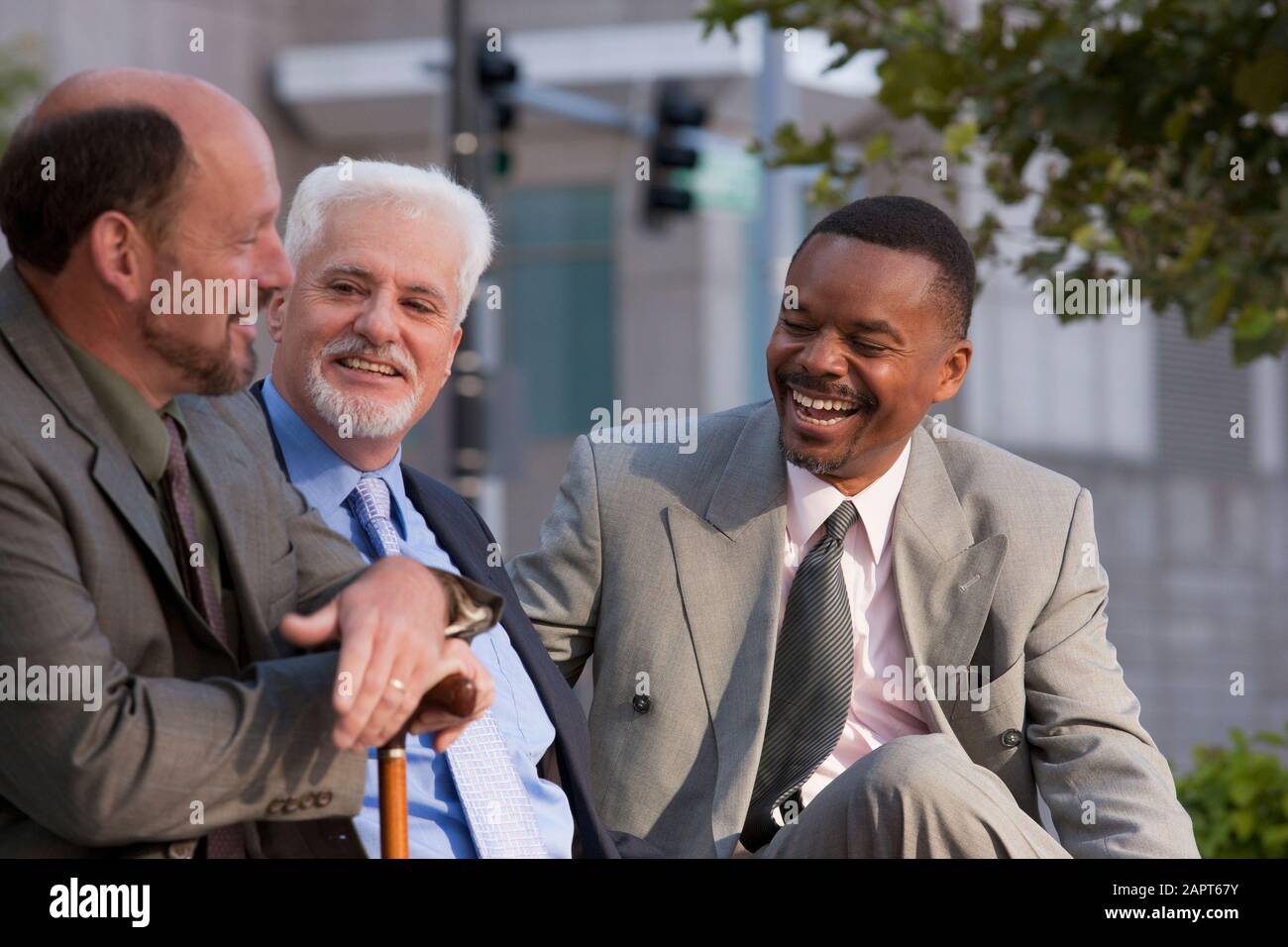 Businessmen talking and sharing insights, with one businessman holding a cane Stock Photo