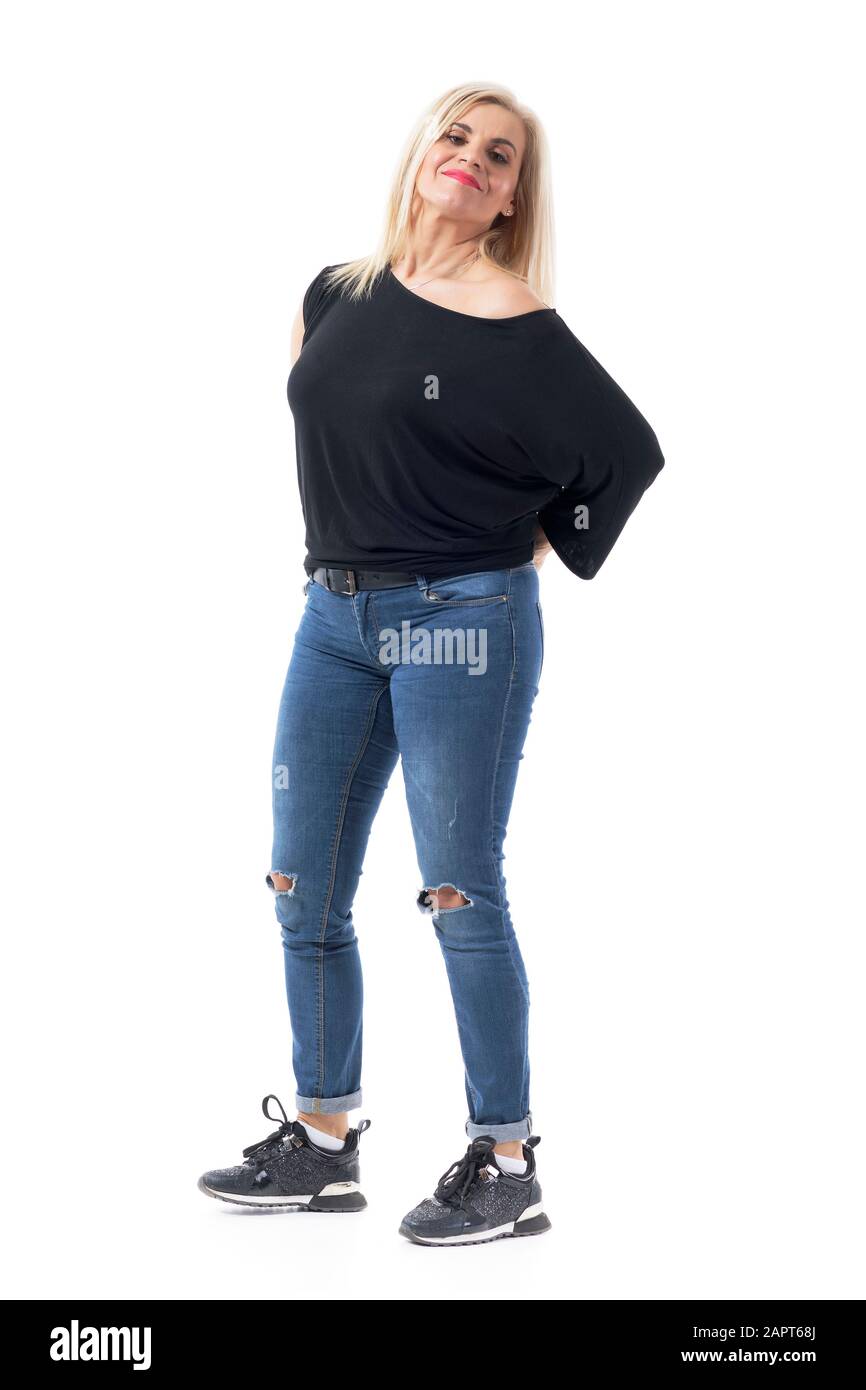 Confident middle aged woman in casual clothes posing with hands behind back looking at camera. Full body length isolated on white background. Stock Photo