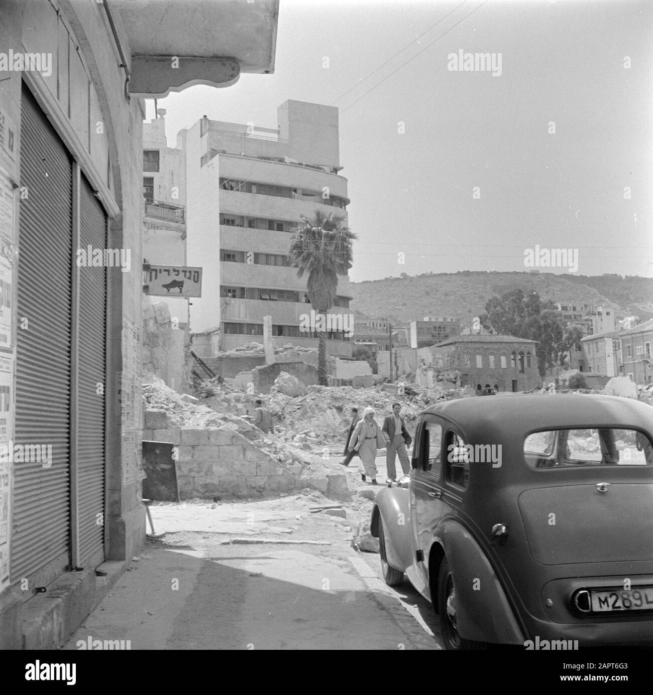 Israel 1948-1949: Haifa  Apartment block in the Arab district, with ruins Date: 1948 Location: Haifa, Israel Keywords: cars, apartment blocks, ruins, pedestrians, homes Stock Photo