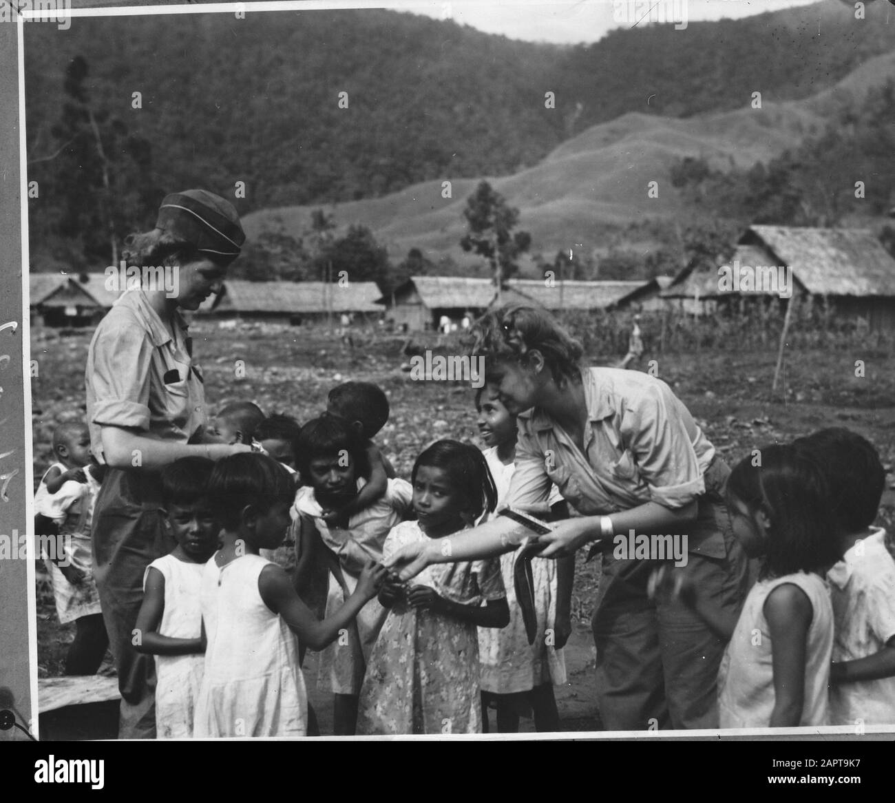 Female NICA officials hand out something to children Annotation: Repronegative Date: 1940-1945 Location: Indonesia, Dutch East Indies Keywords: children, military, Second World War, women Stock Photo