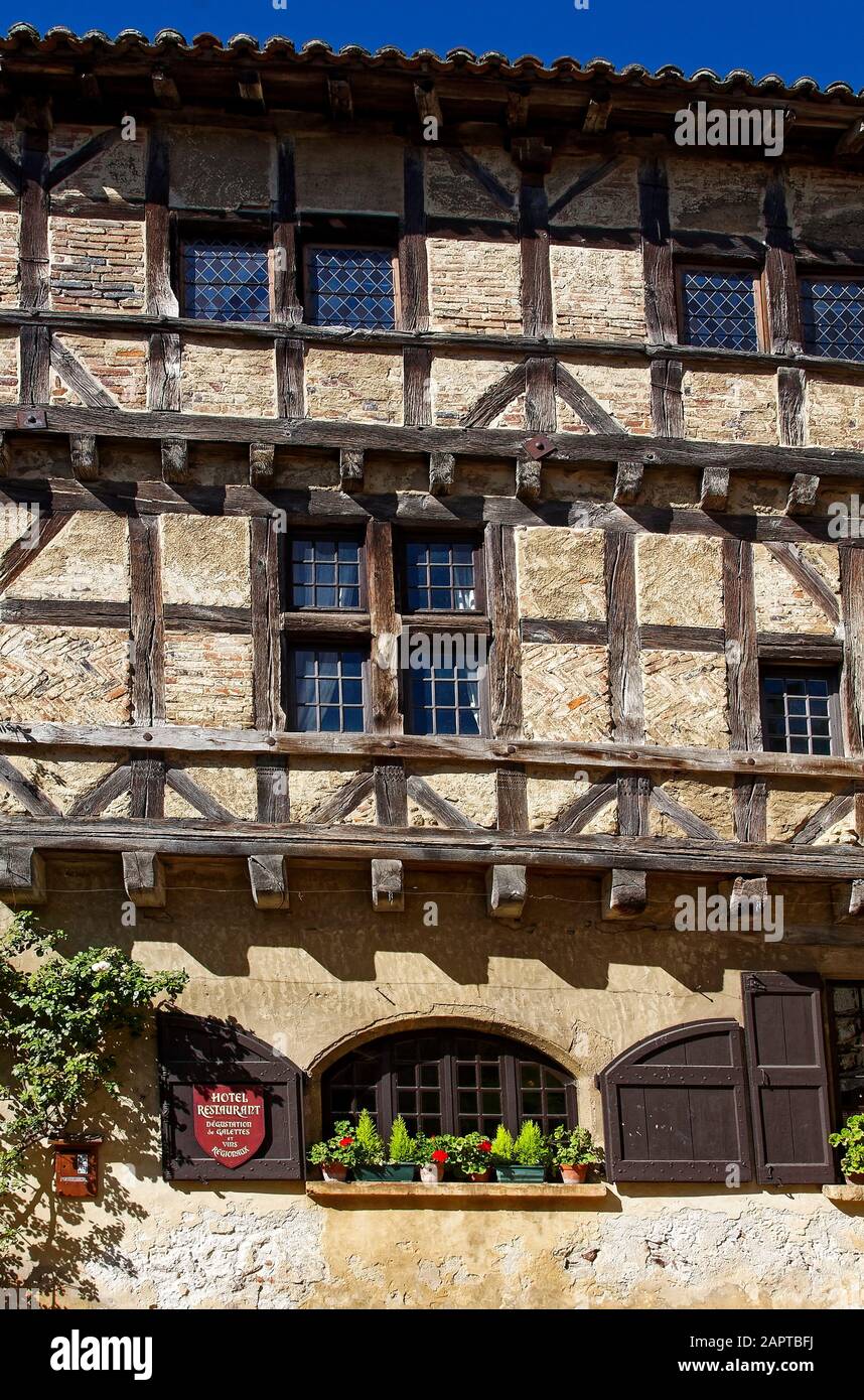 old half-timbered building, brick, stucco, wood, multiple windows, potted plants, hotel restaurant, Perouges, France, summer; vertical Stock Photo