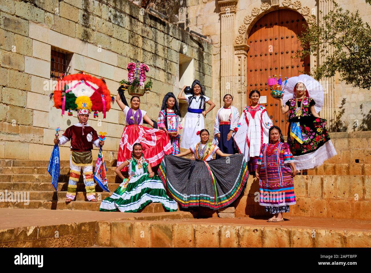 Group of people in traditional Mexican clothing posing in midday sun at door of large church Stock Photo