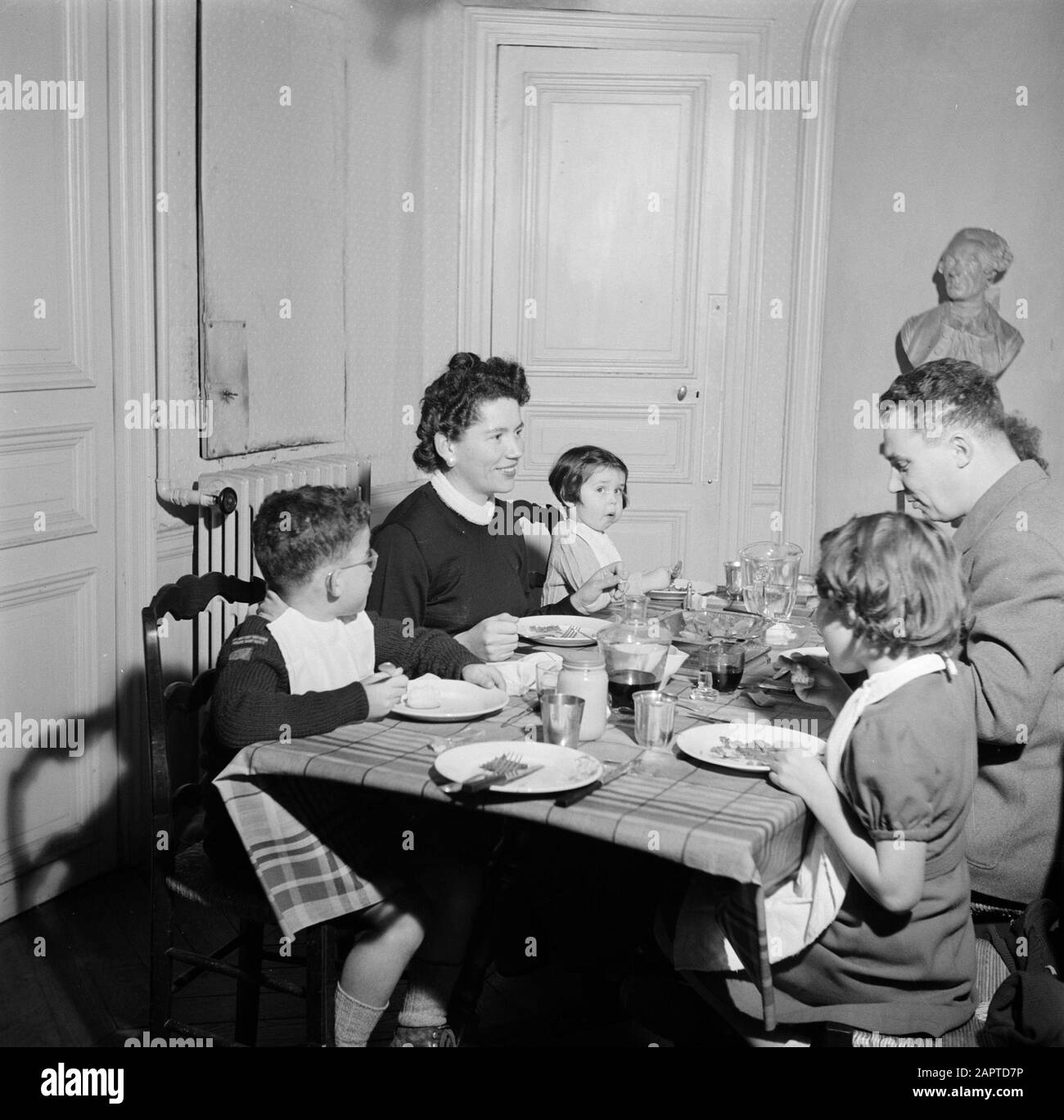 Residents of an apartment building in Paris  Family at the table during the meal Date: 1950 Location: France, Paris Keywords: families, children, meals, crockery, tables Stock Photo