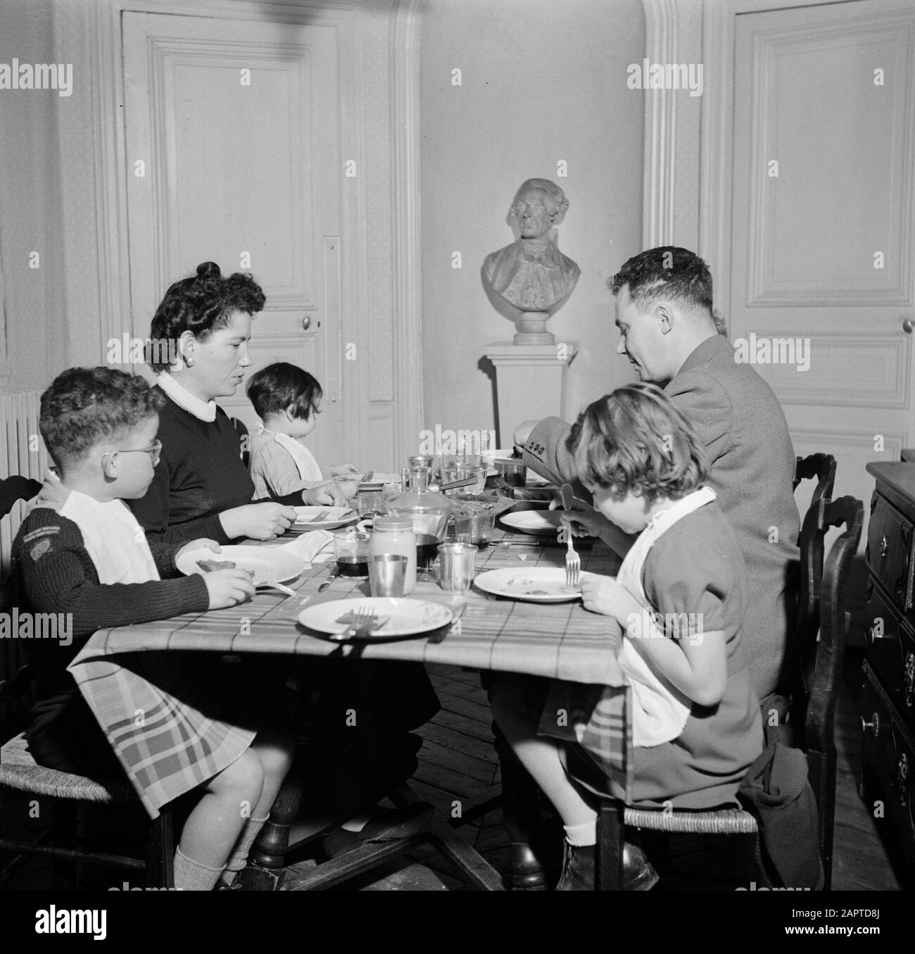Residents of an apartment building in Paris  Family at the table during the meal Date: 1950 Location: France, Paris Keywords: sculptures, families, children, meals, crockery Stock Photo