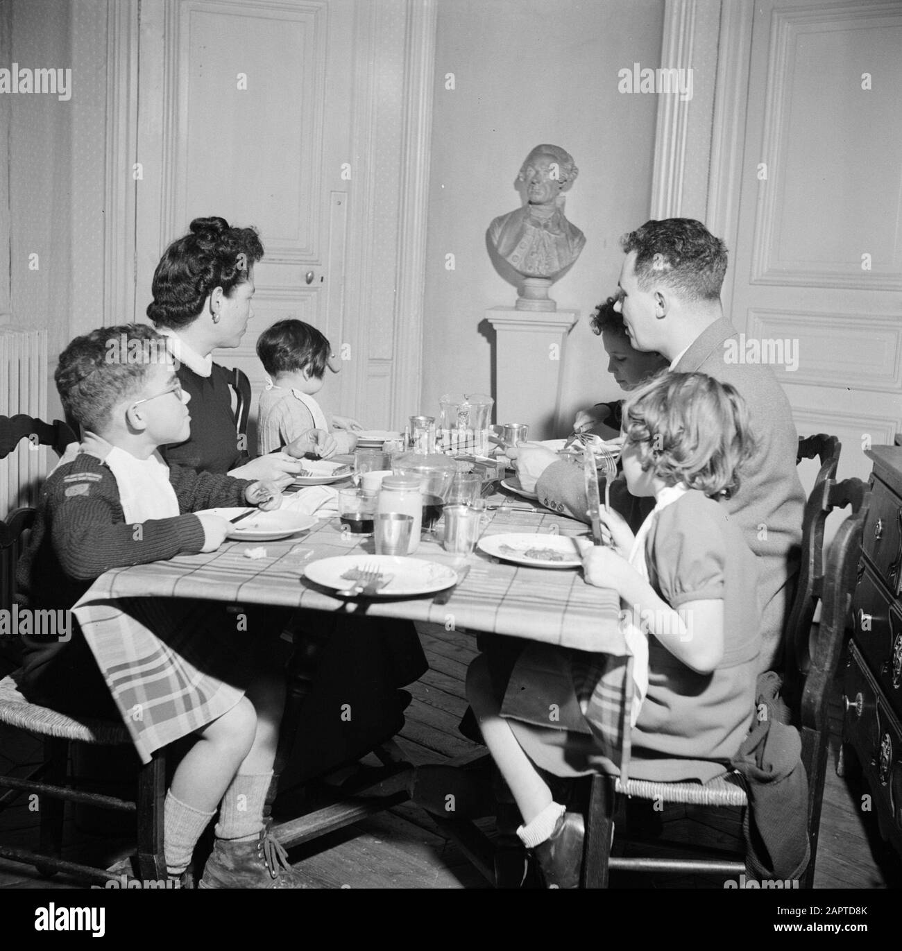 Residents of an apartment building in Paris  Family at the table during the meal Date: 1950 Location: France, Paris Keywords: sculptures, families, children, meals, crockery Stock Photo