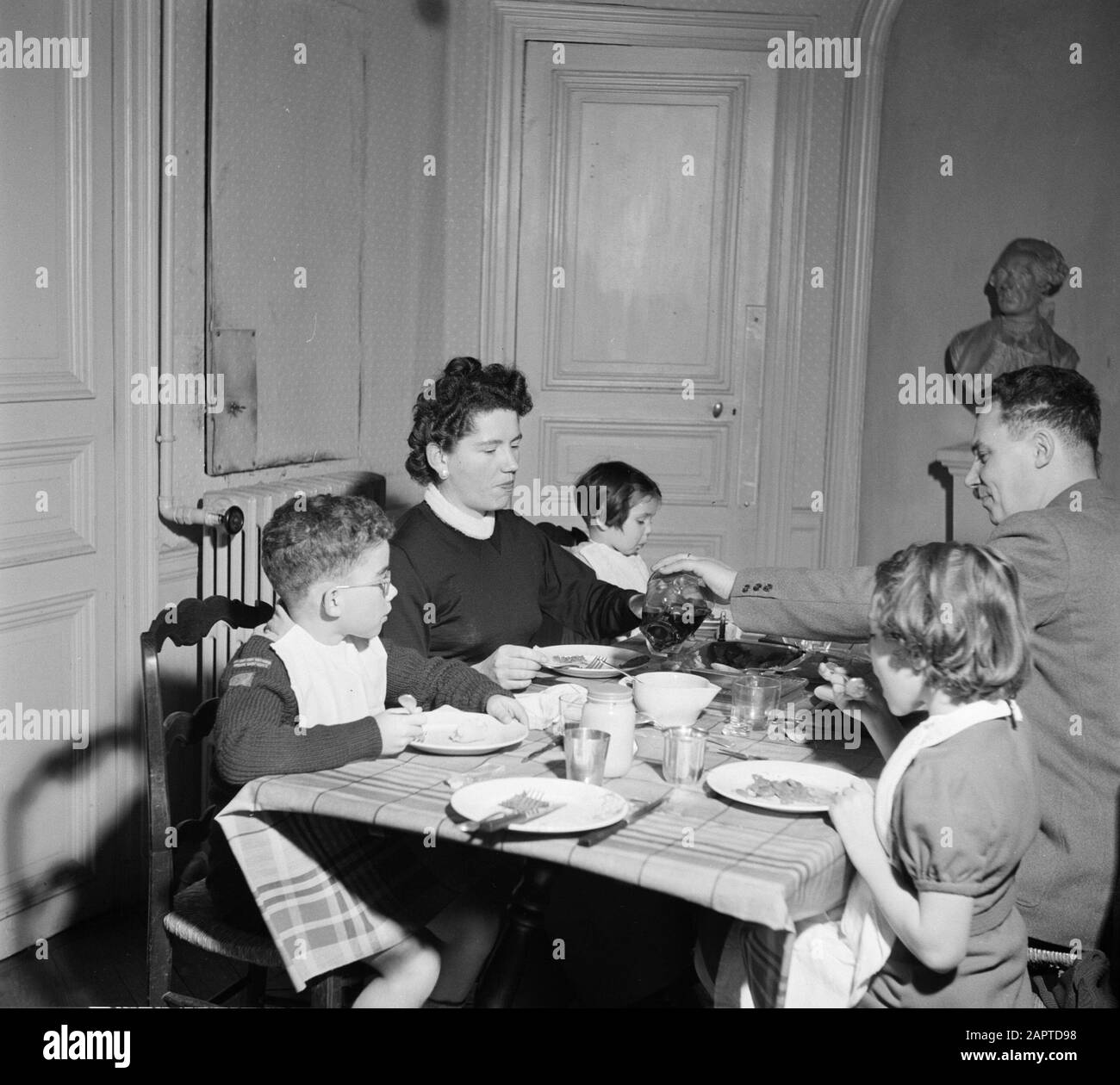 Residents of an apartment building in Paris  Family at the table during the meal Date: 1950 Location: France, Paris Keywords: families, children, meals, crockery, wine Stock Photo