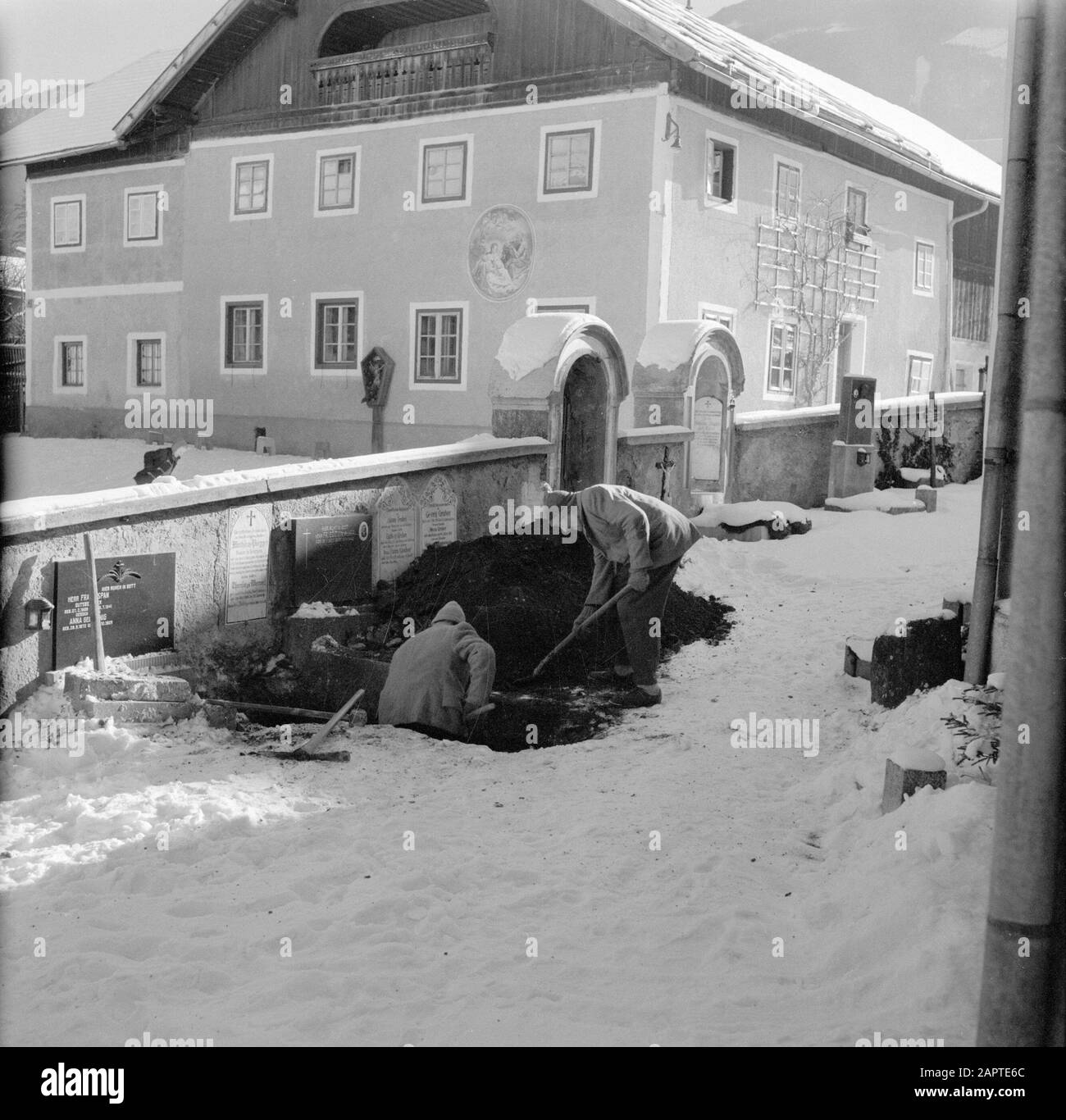 Winter in Tirol  Gravediggers at work in the snow Date: January 1960 Location: Austria, Sistrans, Tyrol Keywords: cemeteries, buildings, graves, snow, winter Stock Photo