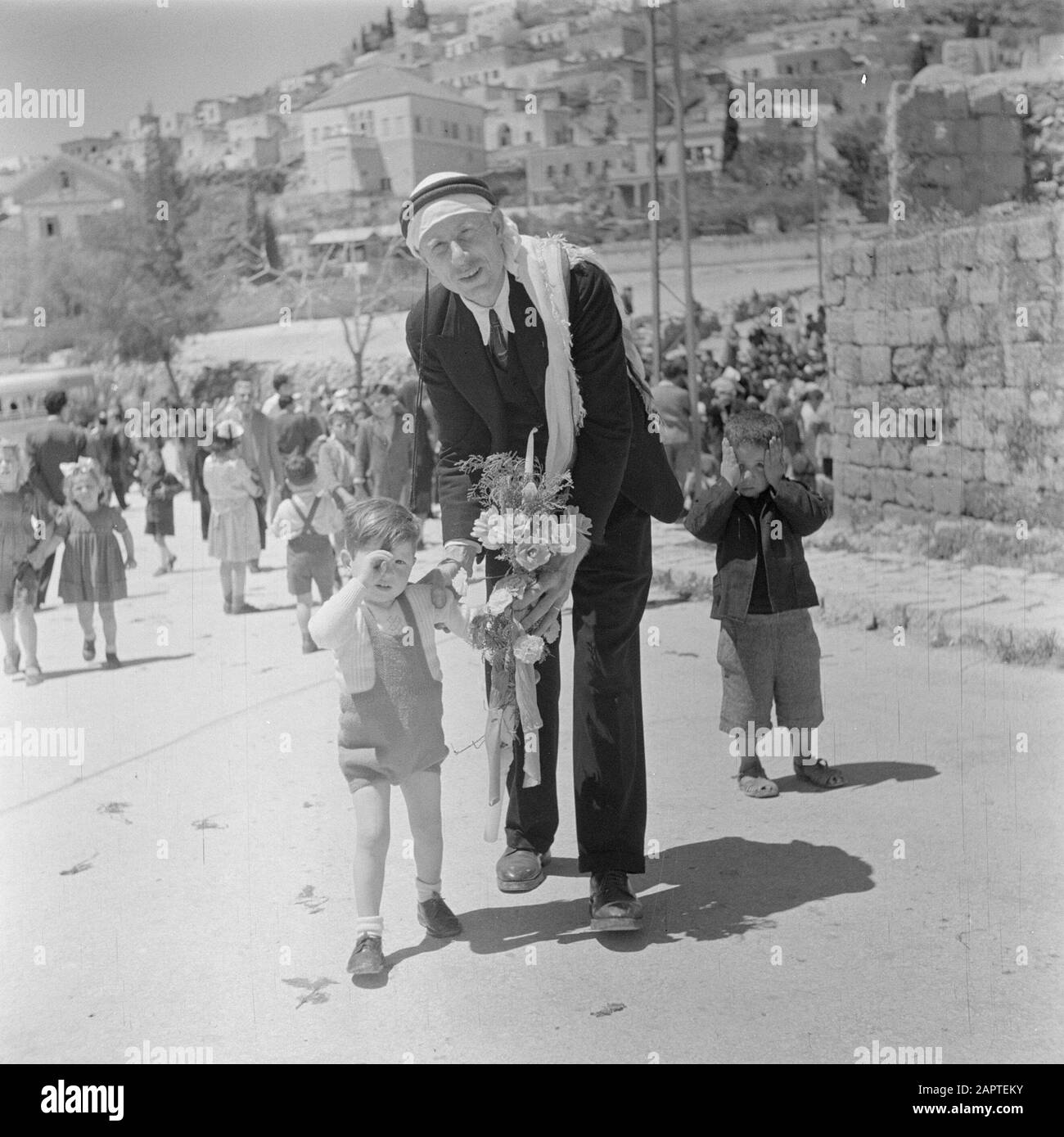 Israel 1948-1949: Galilee  Greek Orthodox father with his son and a decorated candle in hand, together with other children at Easter morning, after a procession in the streets of Nazareth Date: 1948 Location: Israel, Nazareth Keywords: candles, children, processions, religious holidays, religious objects, street images Stock Photo
