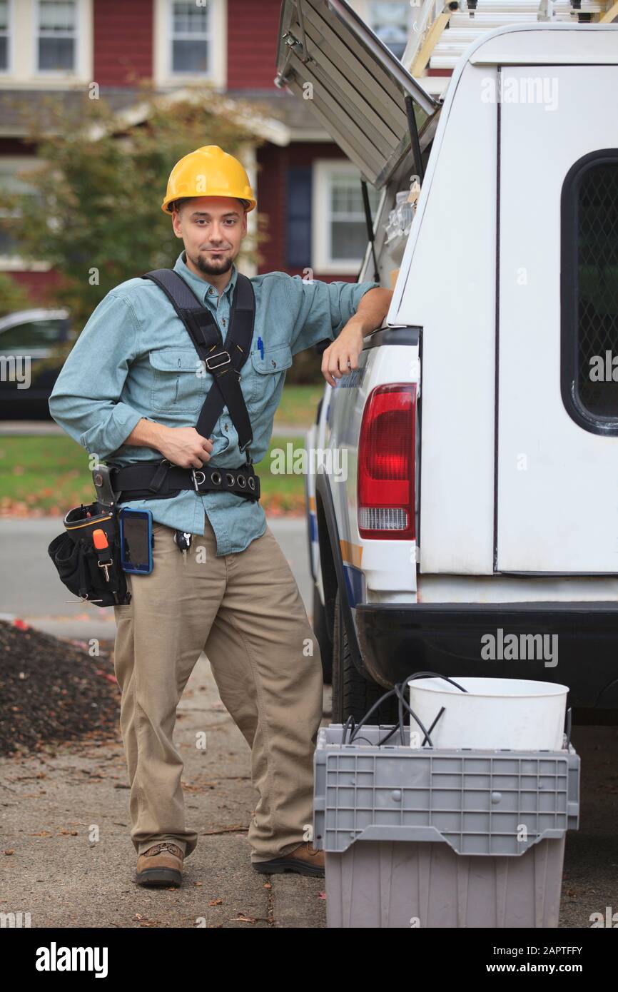 Tradesman retrieving supplies from an open hatch on the side of his work truck Stock Photo