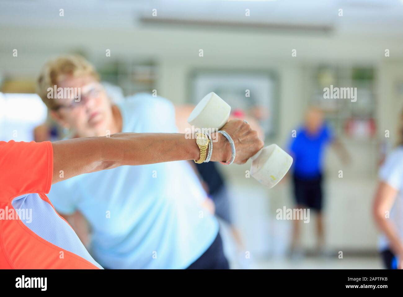 Female instructor lifting free weights in a senior's fitness class Stock Photo