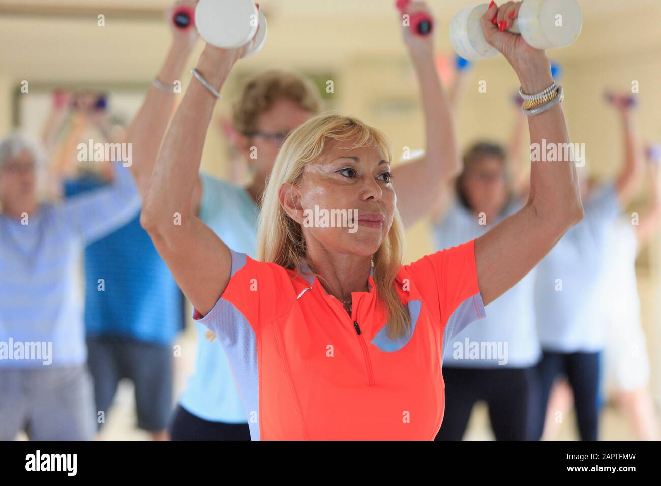 Female instructor lifting free weights in a senior's fitness class Stock Photo