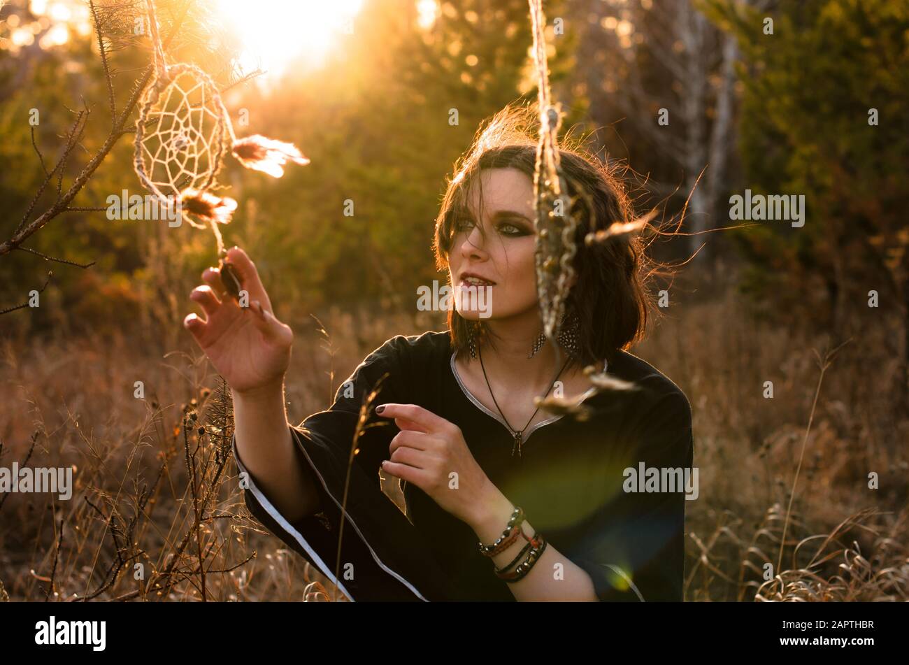 Boho woman with short windy hair. Female silhouette with dream catcher through the sun rays Stock Photo