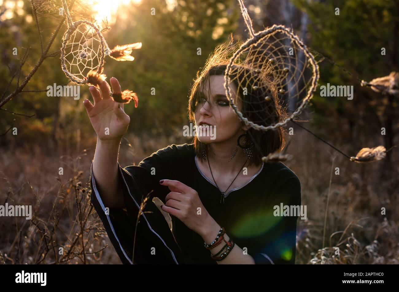 Boho woman with short windy hair. Female silhouette with dream catcher through the sun rays Stock Photo