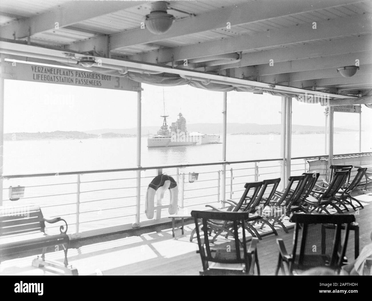 Sea voyage with MS Johan van Oldenbarnevelt to Norway  The British battleship Nelson seen from the deck in the waters at Oslo Date: 1933 Location: Great Britain, Norway, Oslo Keywords: cruises , cruise ships, fences, military vessels, fun, life-saving equipment, ships, battleships, chairs, tourism Stock Photo