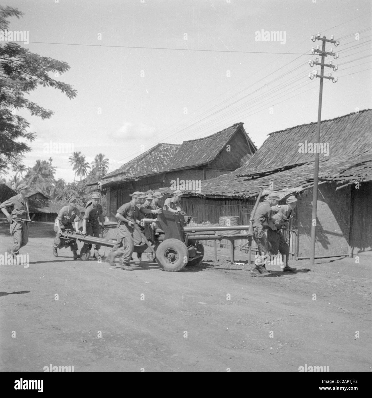 War volunteers in Malacca and Indonesia  Setting up light artillery in a kampong Date: March 1946 Location: Indonesia, Indonesia, Java, Dutch East Indies Keywords: artillery, villages, military Stock Photo