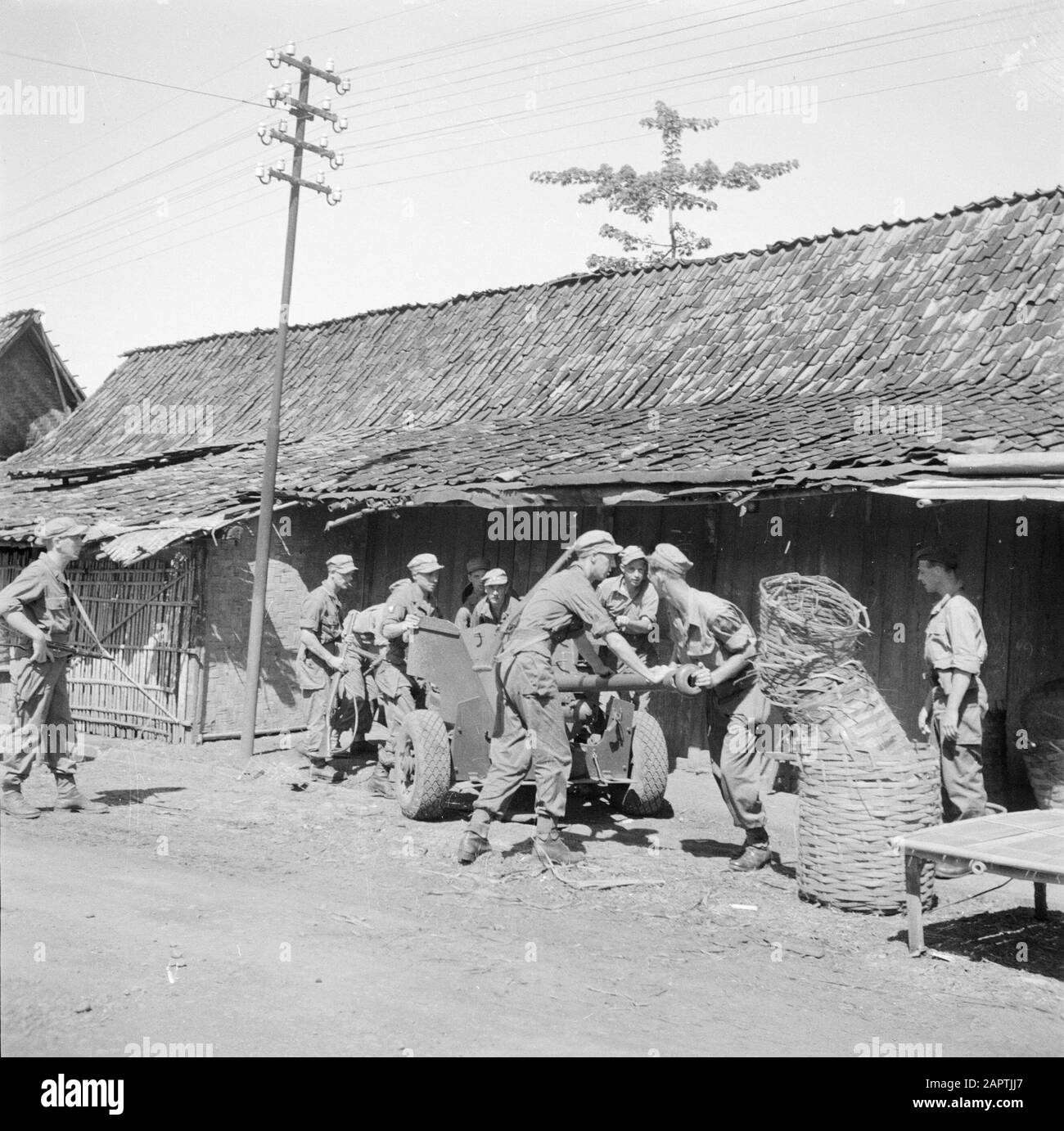 War volunteers in Malacca and Indonesia  Setting up light guns in a kampong Date: March 1946 Location: Indonesia, Indonesia, Java, Dutch East Indies Keywords: villages, artillery , military Stock Photo