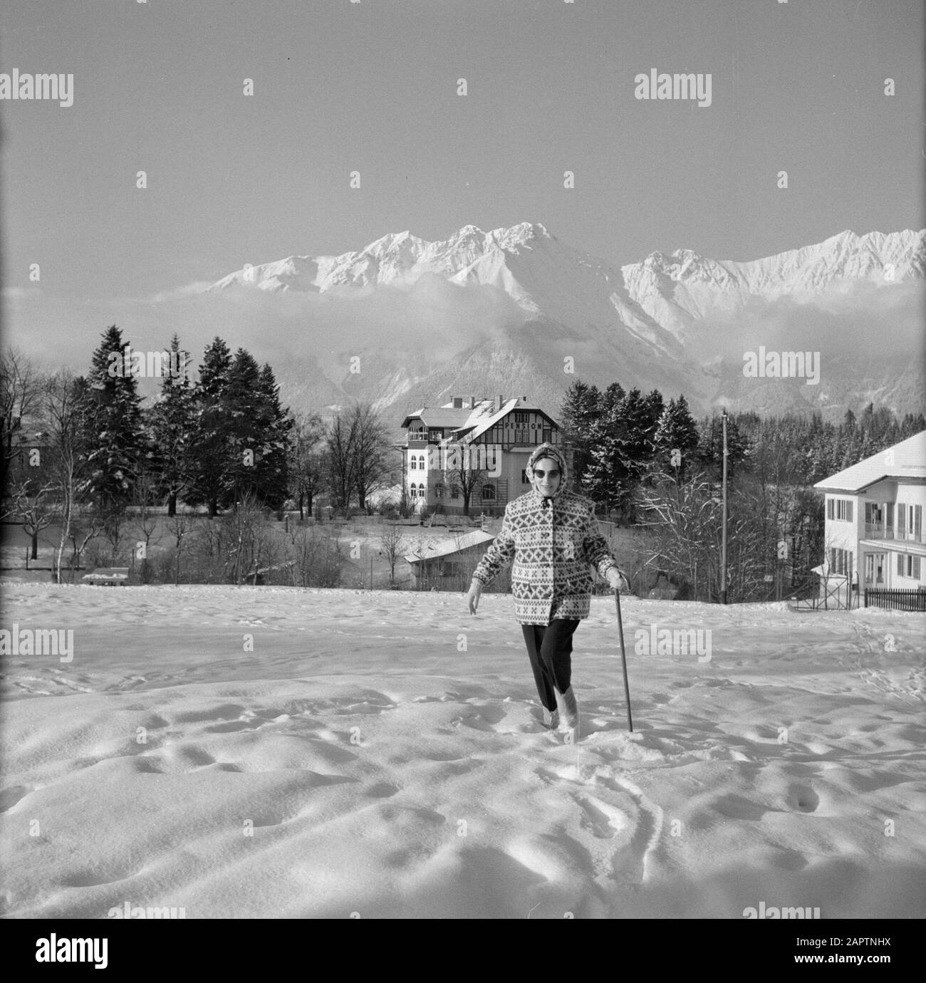 Winter in Tyrol  Hilde Eschen walks in the snow near Sistrans with in the background the Karwendel Mountains Date: January 1960 Location: Austria, Sistrans, Tyrol Keywords: mountains, villages, landscapes, snow, holidays, hiking, winter, residences Personal name: Echen, Hilde Stock Photo