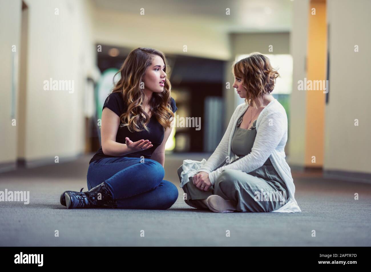 A young woman and her youth leader discussing their faith in a hallway of a church: Edmonton, Alberta, Canada Stock Photo