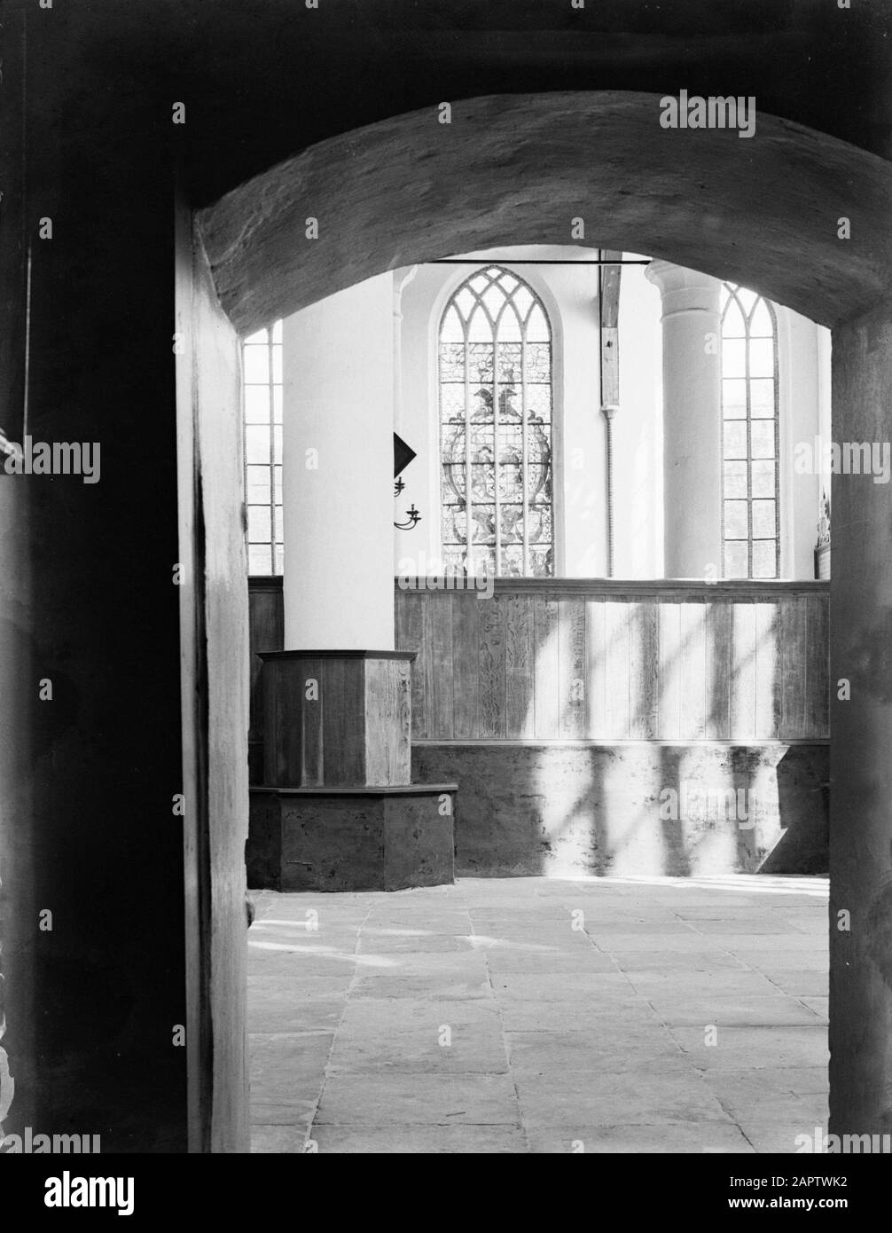 Great or Saint Nicholas Church in Edam  Interior of the Grote Kerk in Edam seen from a portal: the choir fence, pillars and a stained glass window Date: 1 January 1932 Location: Edam, North Holland Keywords: architecture, stained glass, interior, church buildings Stock Photo