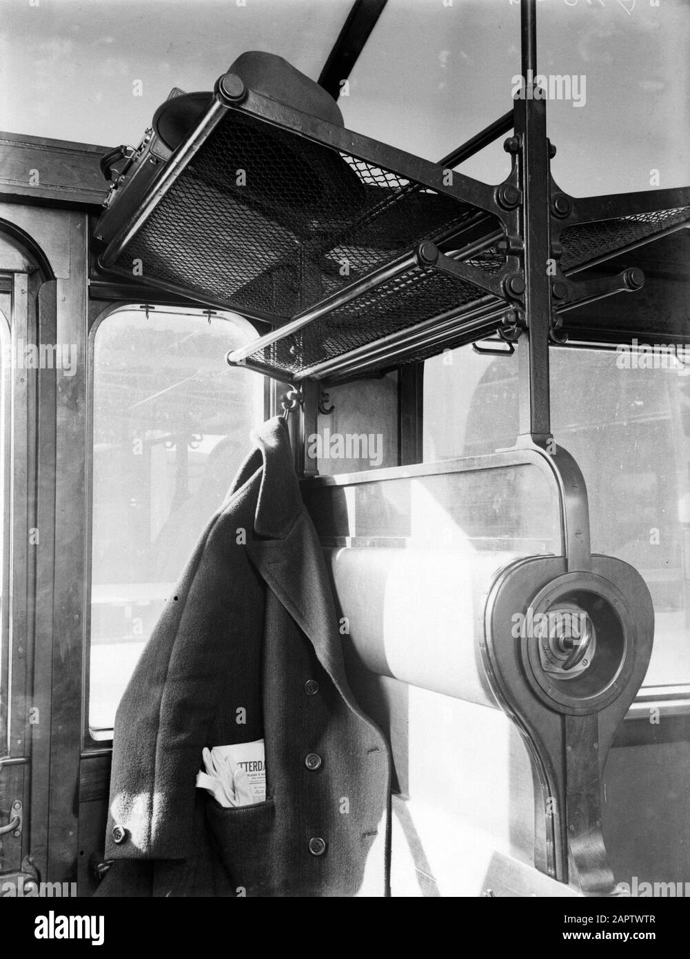Reportage Nederlandse Spoorwegen  Interior of a train oupé: hanging jacket with newspaper in inner pocket, suitcase, luggage racks and benches Annotation: In the jacket an axemplaar of the Nieuwe Rotterdamsche - Courant. - Yeah. Date: 1932 Location: Amsterdam, Noord-Holland Keywords: interior, newspapers, railways, wagons Stock Photo