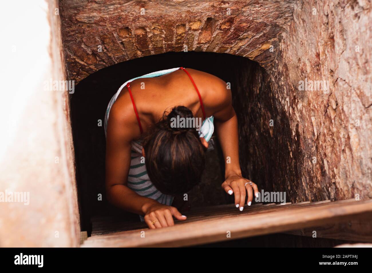 Girl climbing down ladder of an old building. Stock Photo