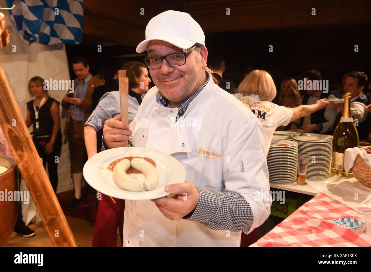 24 January 2020, Austria, Kitzbühel: At the Weißwurstparty in the Stanglwirt, one day before the legendary Hahnenkamm Race, presenter Elton holds Weißwurst on a plate in his hand. The events surrounding the Streif are among the most important celebrity events of the year in Austria. Photo: Felix Hörhager/dpa Stock Photo