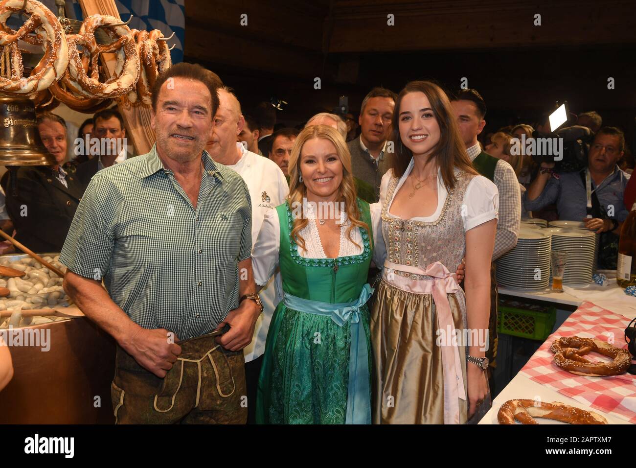24 January 2020, Austria, Kitzbühel: Actor Arnold Schwarzenegger (l) whose daughter Christina (r) and Schwarzenegger's girlfriend Heather Milligan (m) are celebrating at the Weißwurst Party at the Stanglwirt, one day before the legendary Hahnenkamm Race. The events surrounding the Streif are among the most important celebrity events of the year in Austria. Photo: Felix Hörhager/dpa Stock Photo