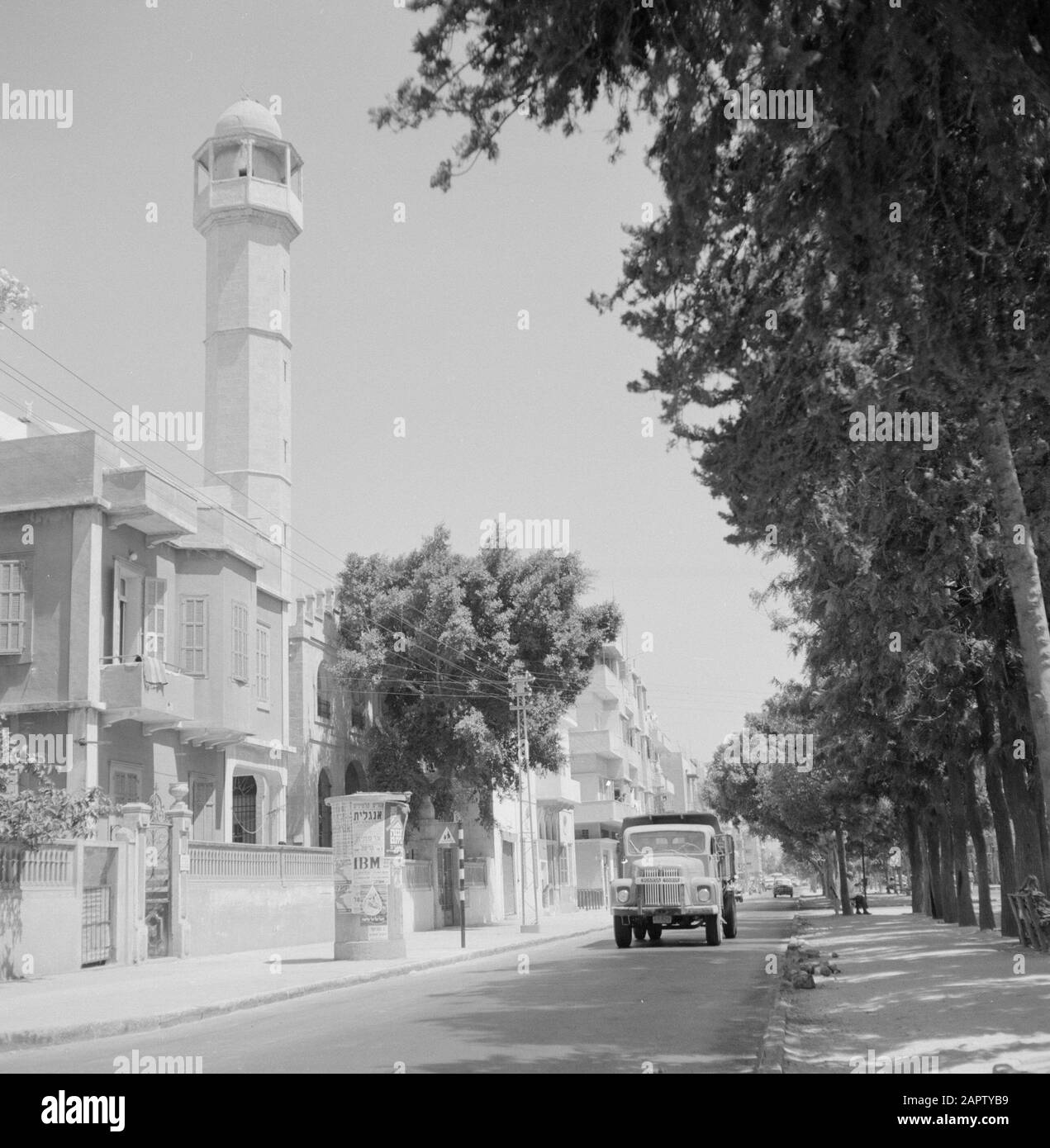 Israel: Jaffa (Tel Aviv)  Jaffa. Street view with a Scania Vabis truck and with a minaret on the left. On the sidewalk an advertising column Annotation: Jaffa is now a city district of Tel Aviv Date: undated Location: Israel, Jaffa, Tel Aviv Keywords: trees, mosques, billboards, street statues, towers, trucks Stock Photo