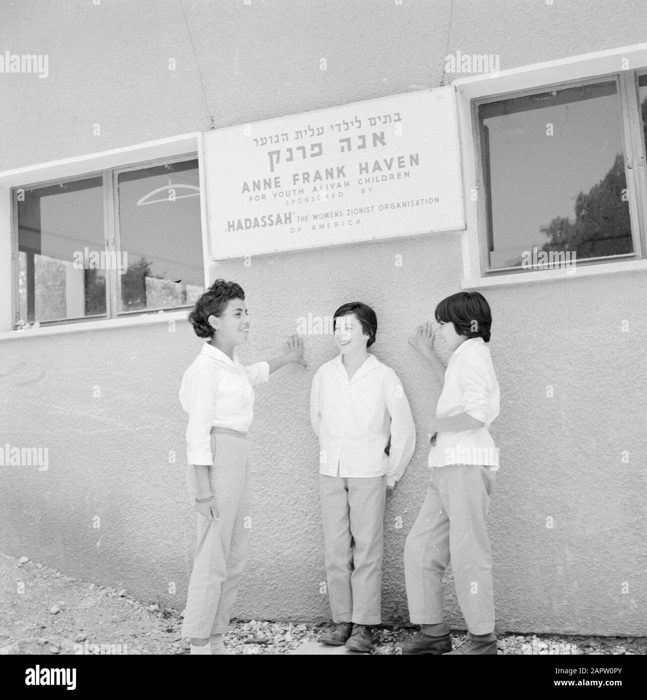 Youth Center Ramat Hadassah. Three girls in front of the Anne Frank Haven with a memorial board against the wall of the sponsor of the Anne Frank Haven, the Zionist women's organization Hadassah in the USA Date: January 1, 1964 Location: Israel, USA Keywords: memorials, child protection, education, pedagogy, sponsorship, women's movement, Zionism Personal name: Frank, Anne Stock Photo