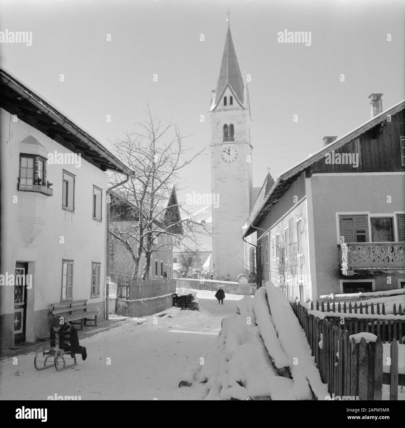 Winter in Tyrol  Child with sleigh in the snow in Sistrans Date: January 1960 Location: Austria, Sistrans, Tyrol Keywords: village statues, church buildings, sleds, snow, holidays, winter sports, winter sports, etc. housing Stock Photo