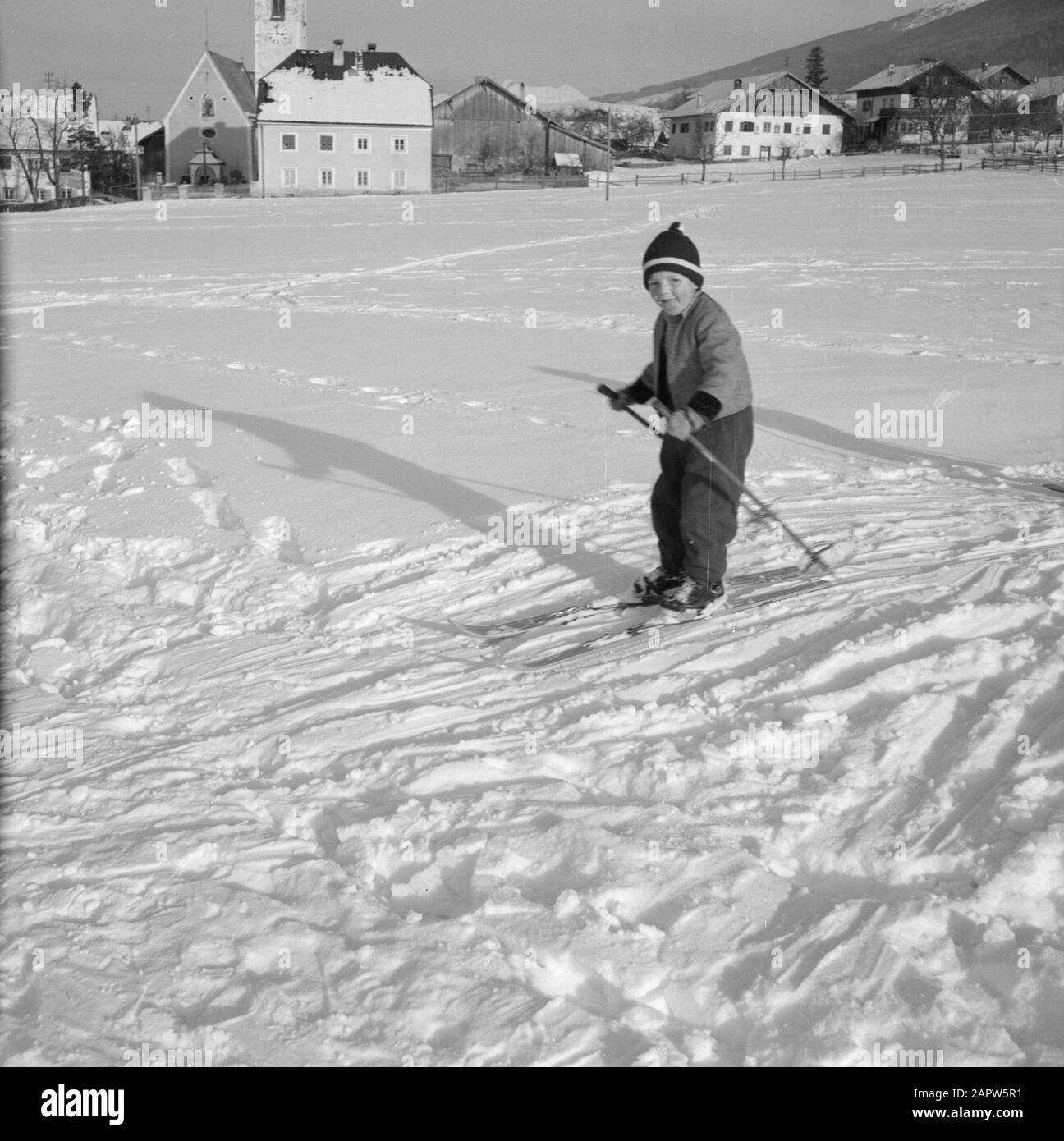 Winter in Tyrol  Child with skis in the snow with in the background Sistrans and the Karwendel Mountains Date: January 1960 Location: Austria, Sistrans, Tyrol Keywords: mountains, landscapes, cross-country skiing, skiing, snow, winter, winter sports Stock Photo