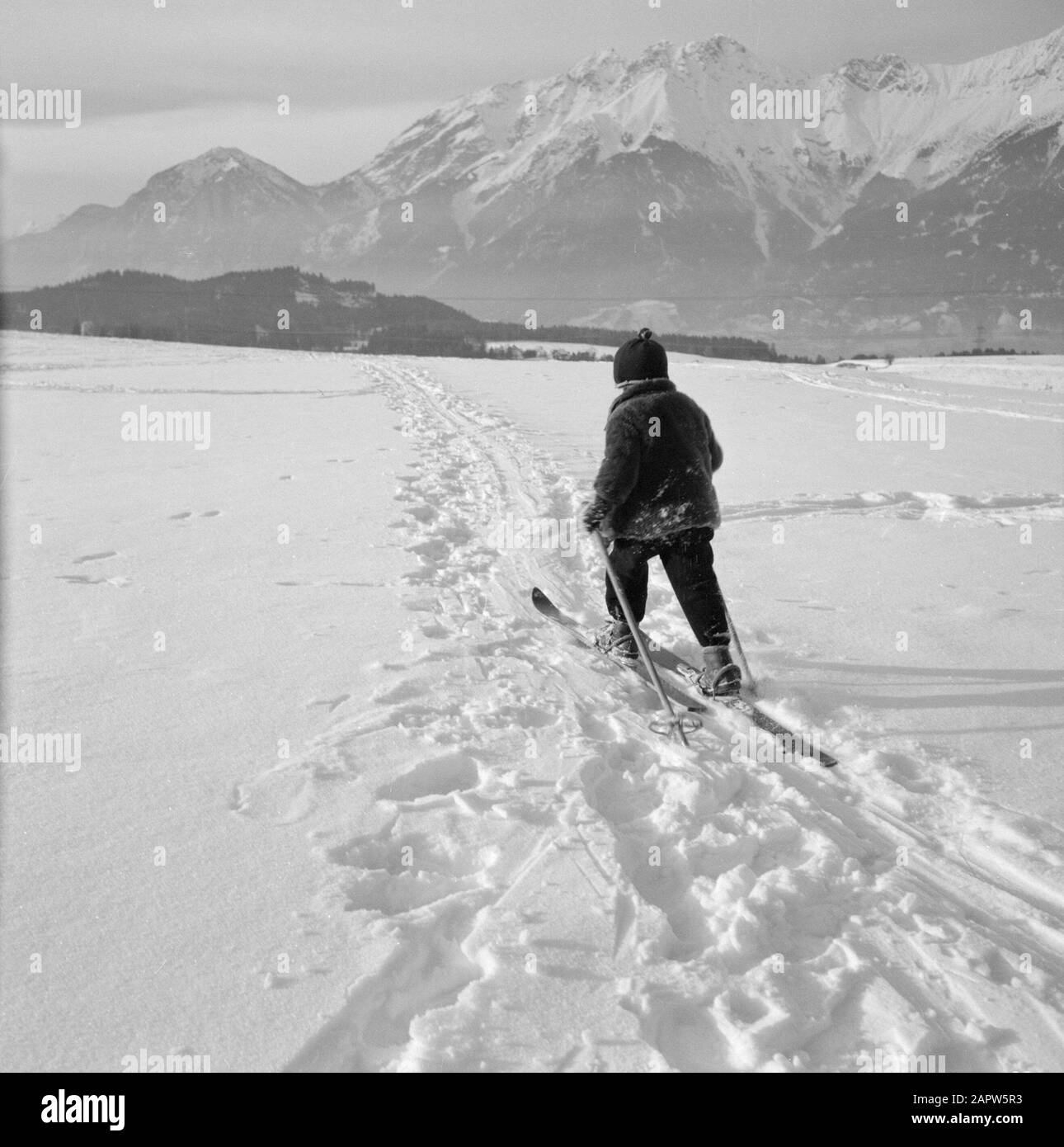 Winter in Tyrol  Child with skis in the snow with the Karwendel Mountains in the background Date: January 1960 Location: Austria, Sistrans, Tyrol Keywords: mountains, landscapes, cross-country skiing, skiing, snow, winter, winter sports Stock Photo