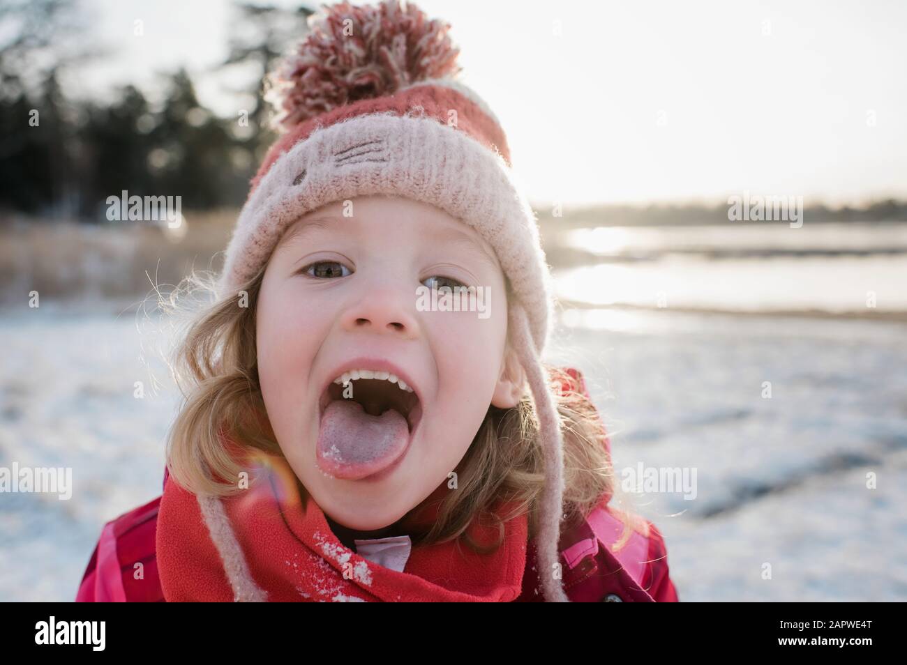 young girl catching snow on her tongue outside in winter Stock Photo