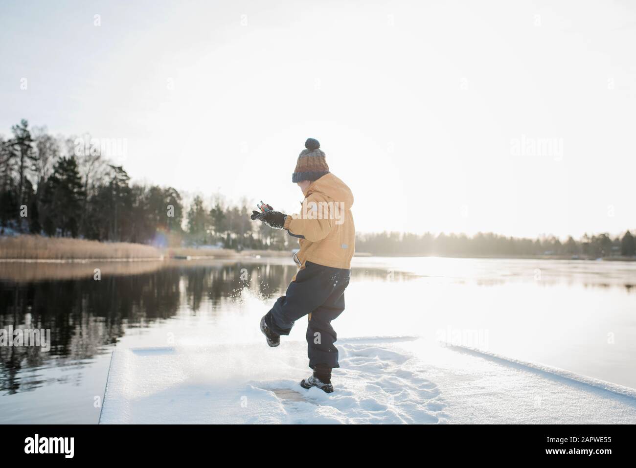 young boy playing in the snow at sunset by the Baltic sea in Sweden Stock Photo