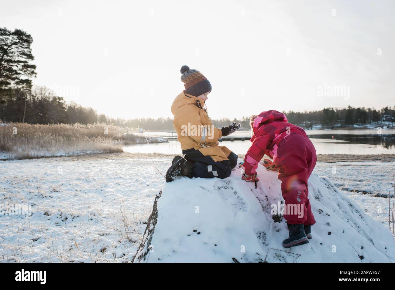 siblings playing together by the Baltic Sea in the snow at winter Stock Photo