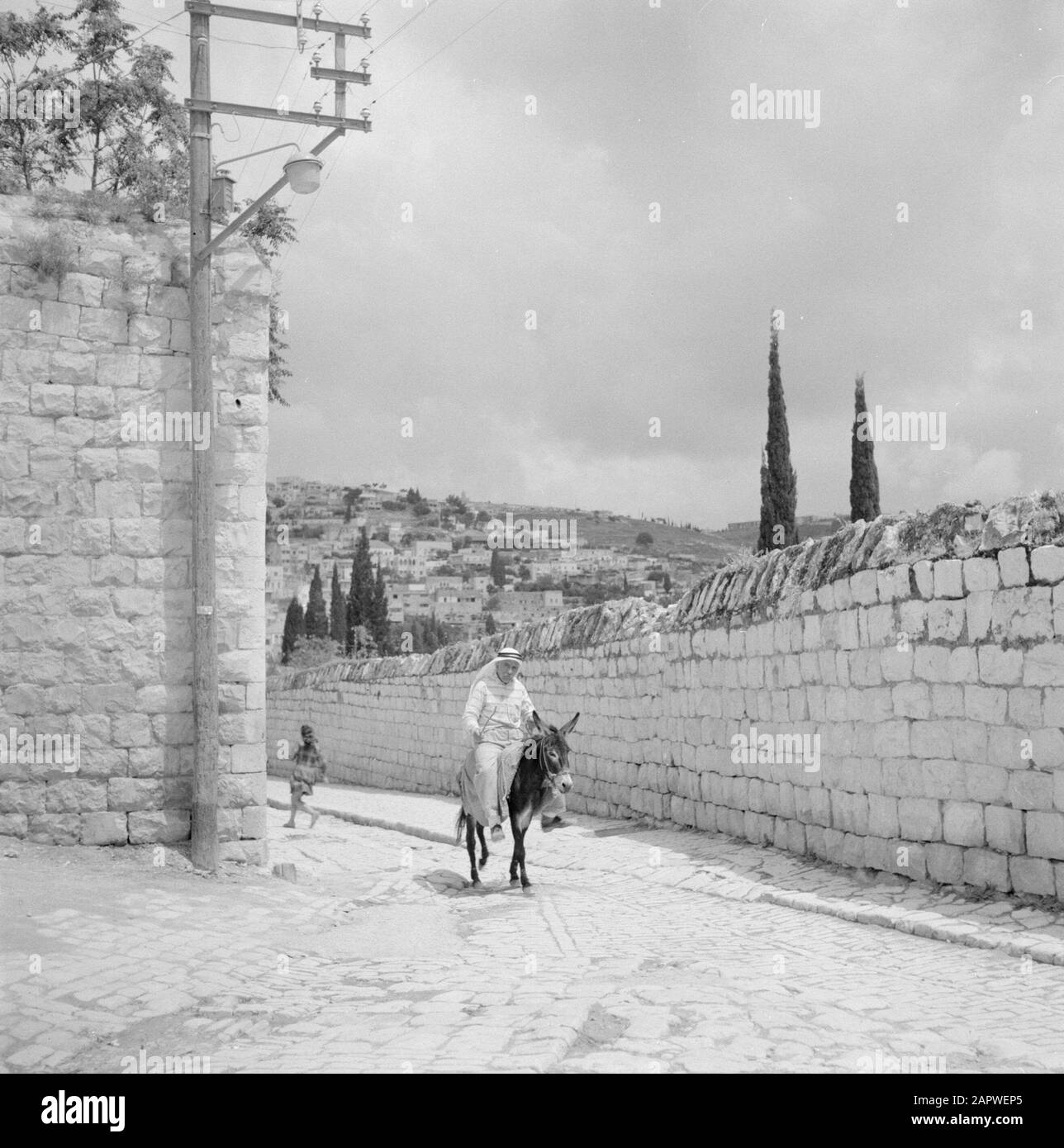 Israel: Nazareth  Man on a donkey, riding along a wall Date: undated Location: Galilee, Israel, Nazareth Keywords: donkeys, men, walls, street images Stock Photo