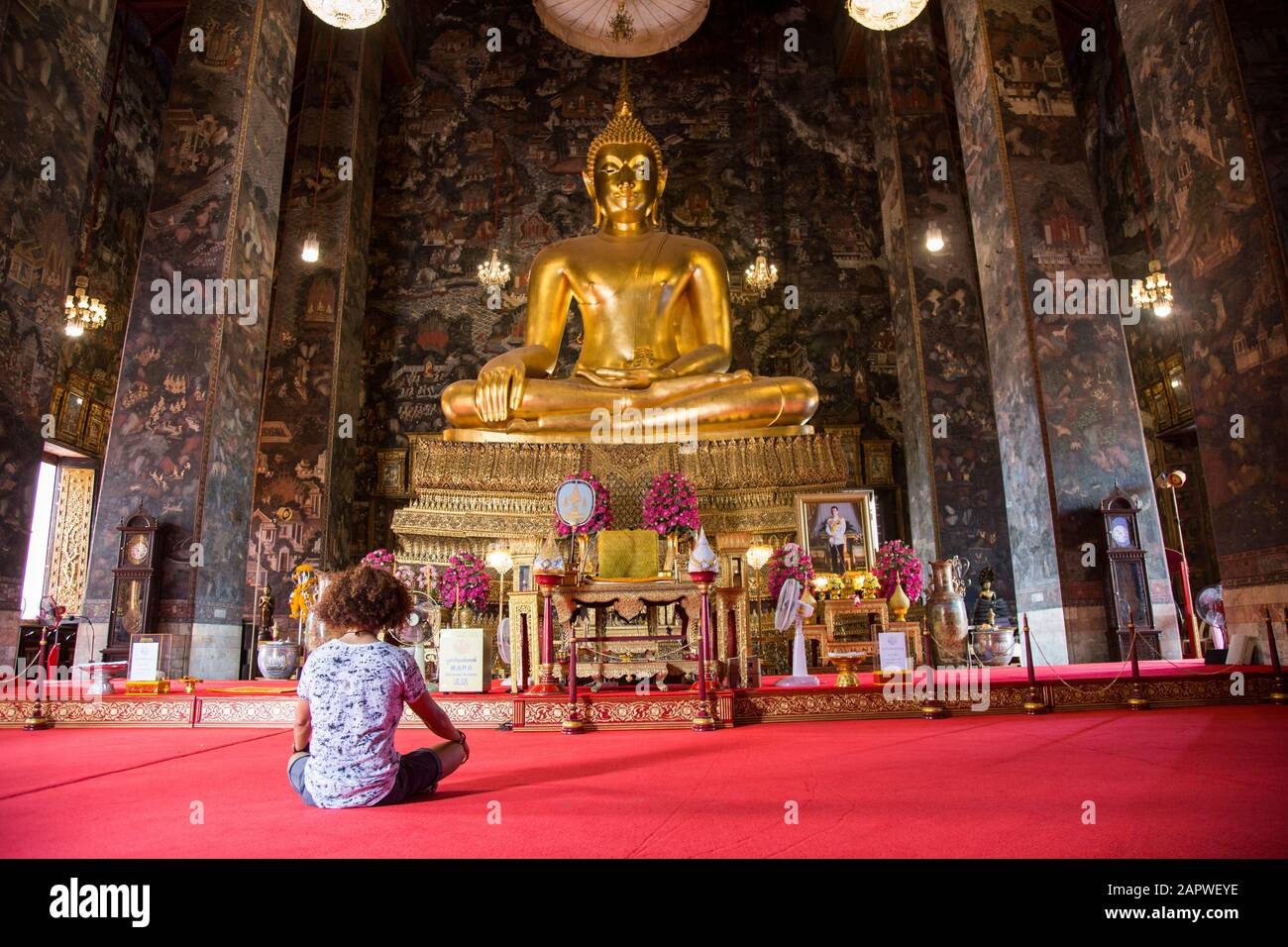 Man with curly hair meditating at Wat Suthat Thepwararam temple Stock Photo