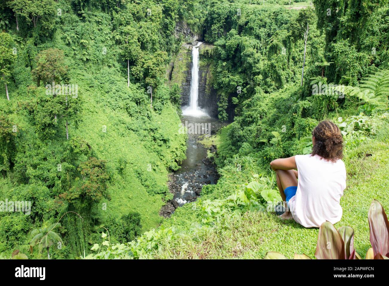 Male tourist with curly hair, looking at exotic Fuipsia waterfall Stock Photo