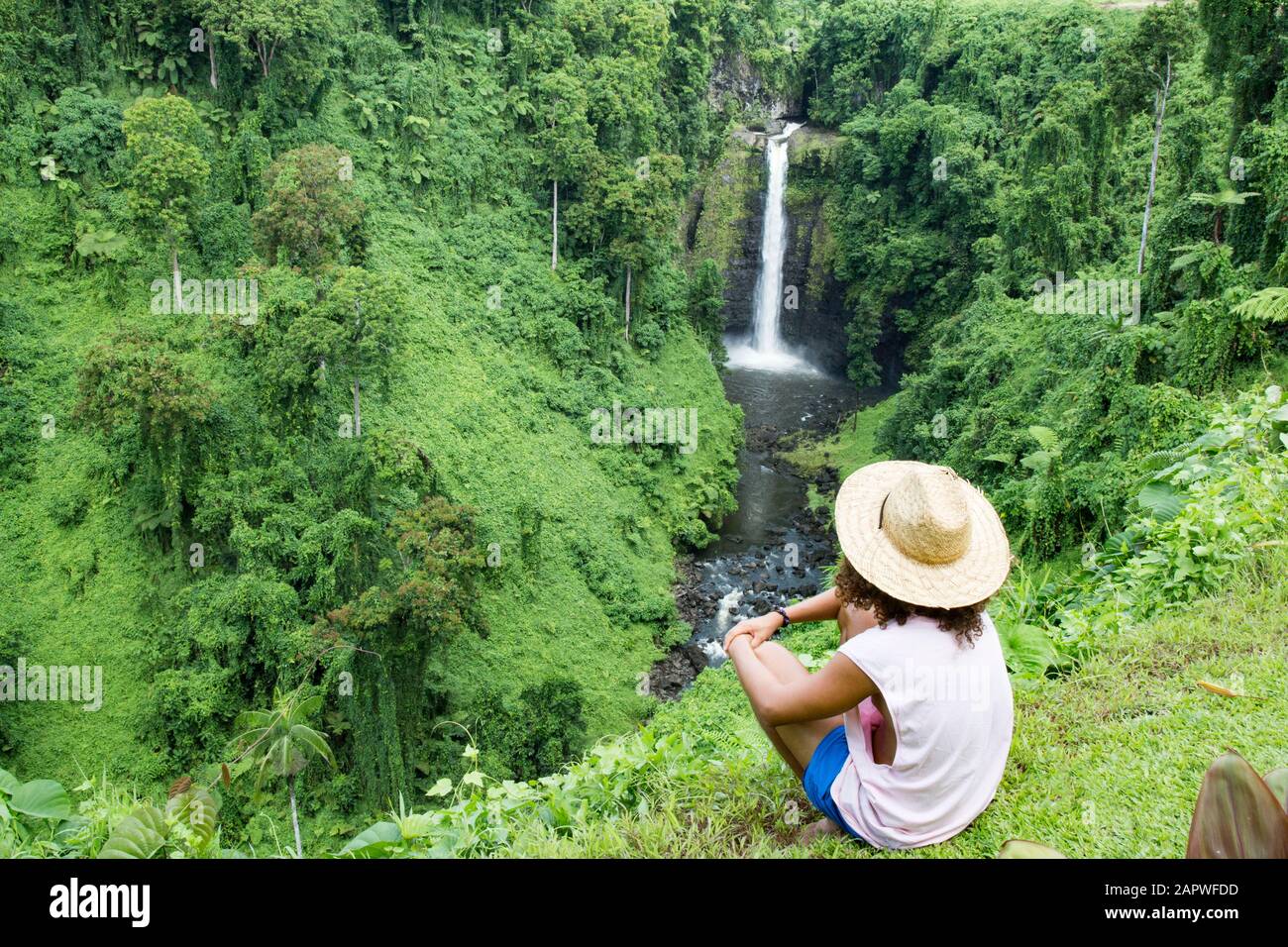 Male tourist with sun hat, looking at exotic Fuipsia waterfall Stock Photo