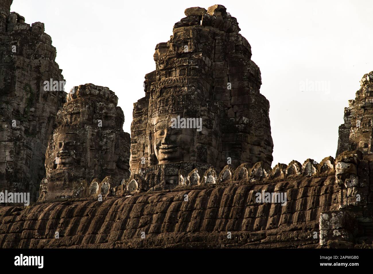 Carved faces on tower at Bayon Temple during sunset, Angkor, Siem Reap Stock Photo