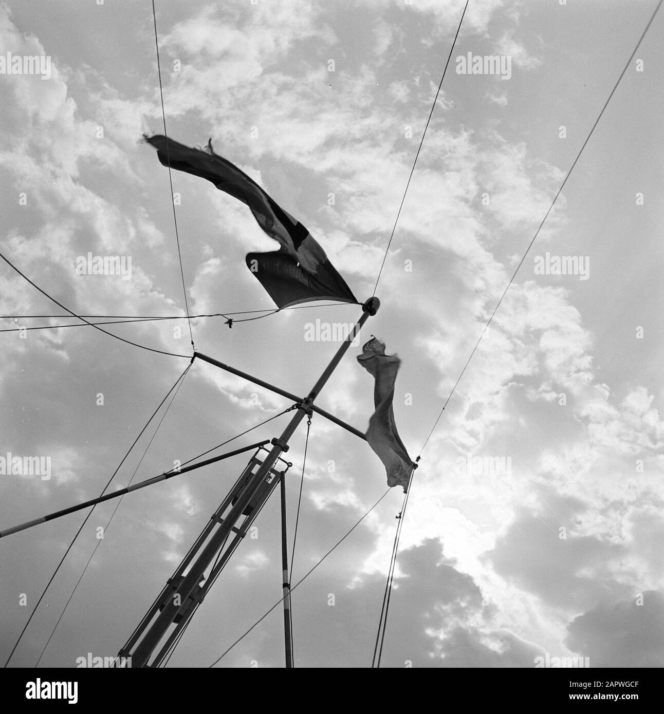 Rijnvaart, report from tugboat Damco 9: Netherlands  Mast with two flags of the tug against a cloud sky near Rotterdam Date: 1 april 1955 Location: Rotterdam, Zuid-Holland Keywords: masts, ships, rigging, flags, clouds Stock Photo