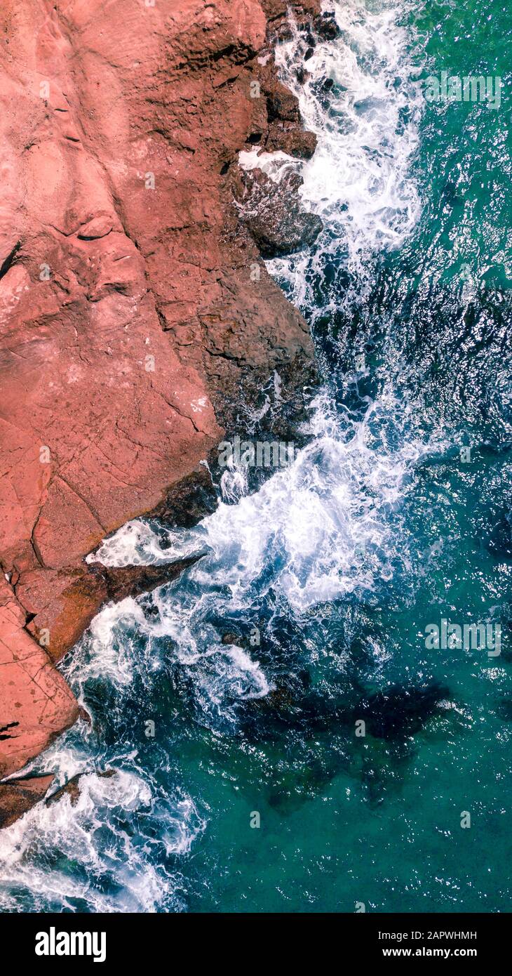 Aerial shot of waves splashing on rocky beach in California Stock Photo