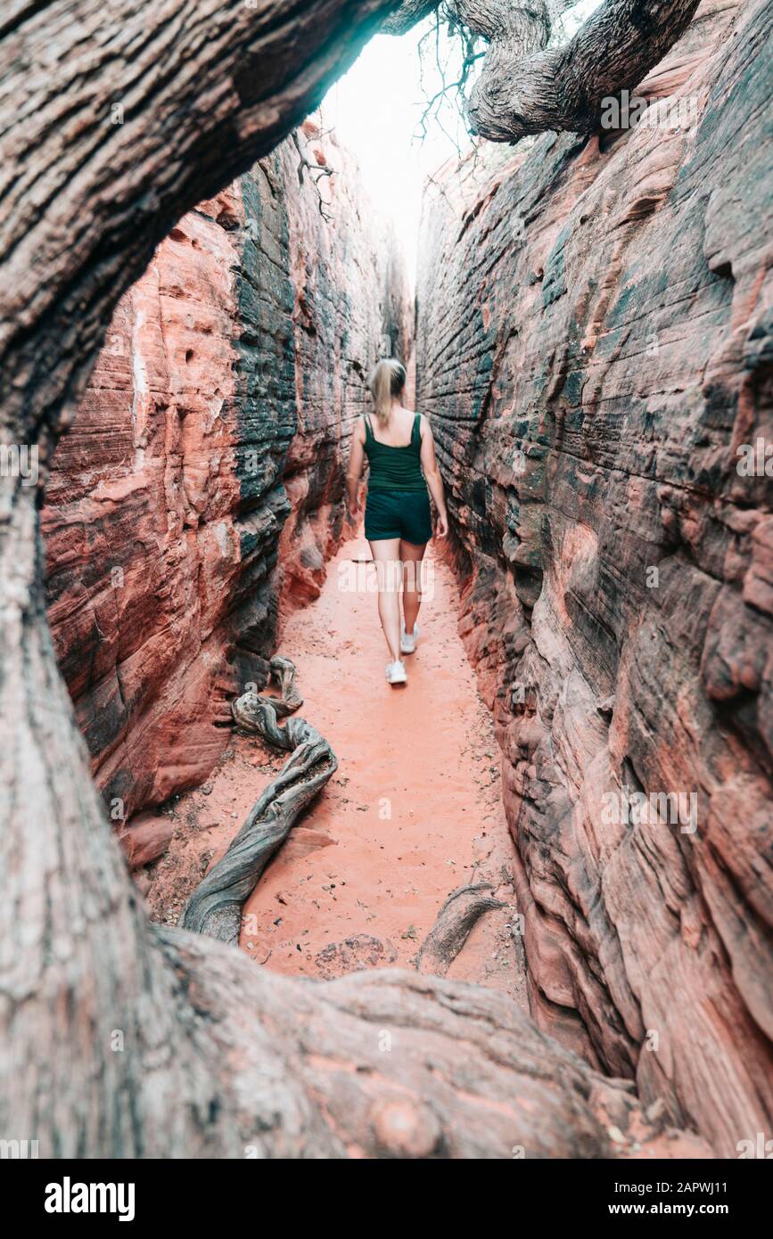 Young female hiking through narrow canyon in Utah Stock Photo