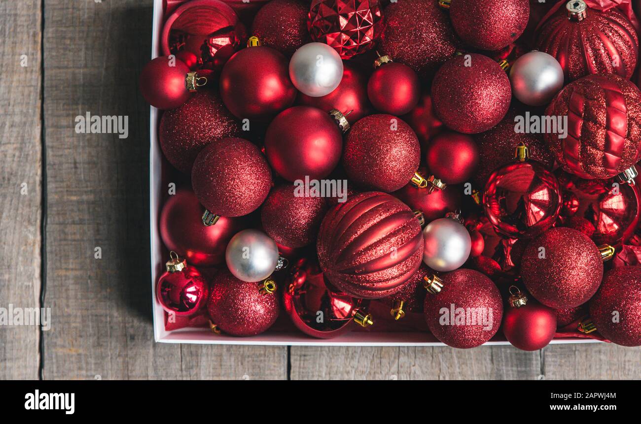 Box of variety of red and white christmas ornaments on a wooden table. Stock Photo