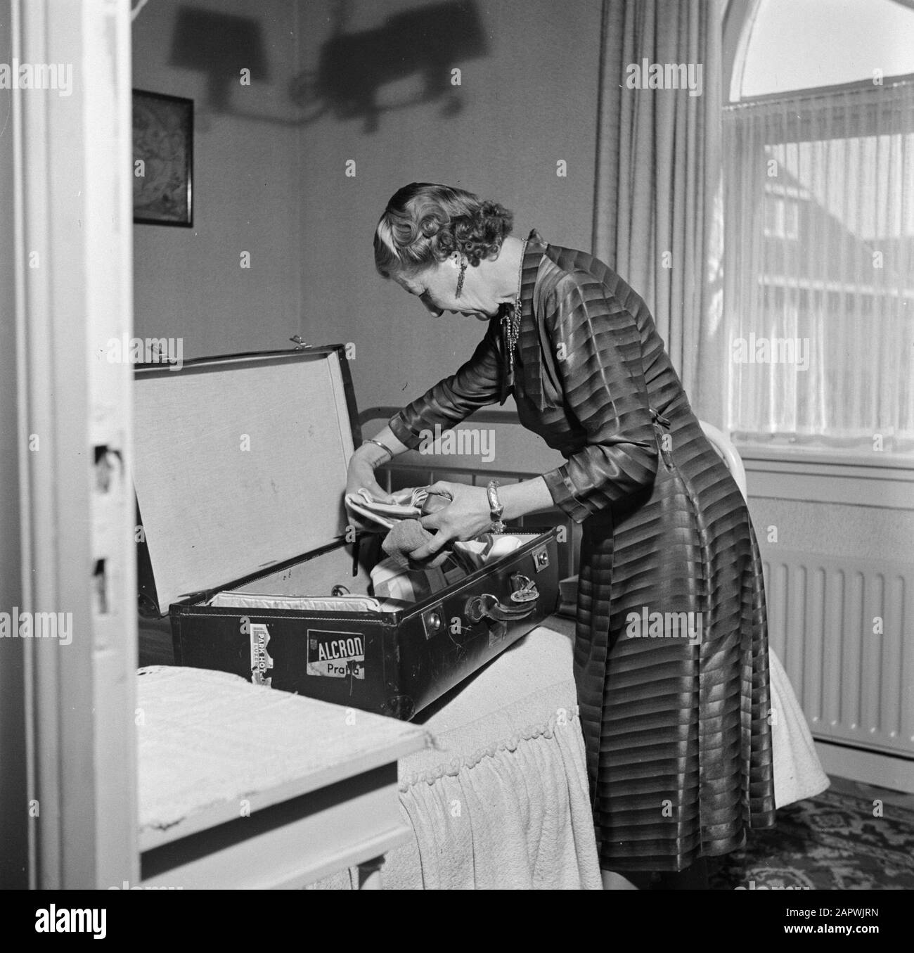 KLM, Buildings, offices, organization  Mrs Dellaert at home when packing a suitcase Annotation: Mr Dellaert (1893-1960) was director of the KLM from 1950 to 1960 Date: May 1954 Location: Amstelveen, Noord-Holland Keywords: packing, interior, suitcases, homes Stock Photo