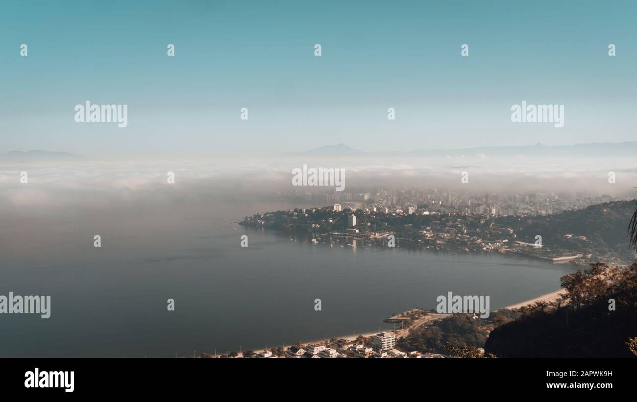 Aerial photo of Rio de Janeiro covered in the fog under a blue sky in ...