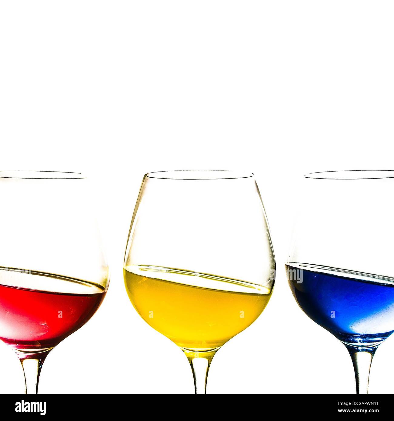 Isolated shot of three glasses filled with yellow, red and blue fluids